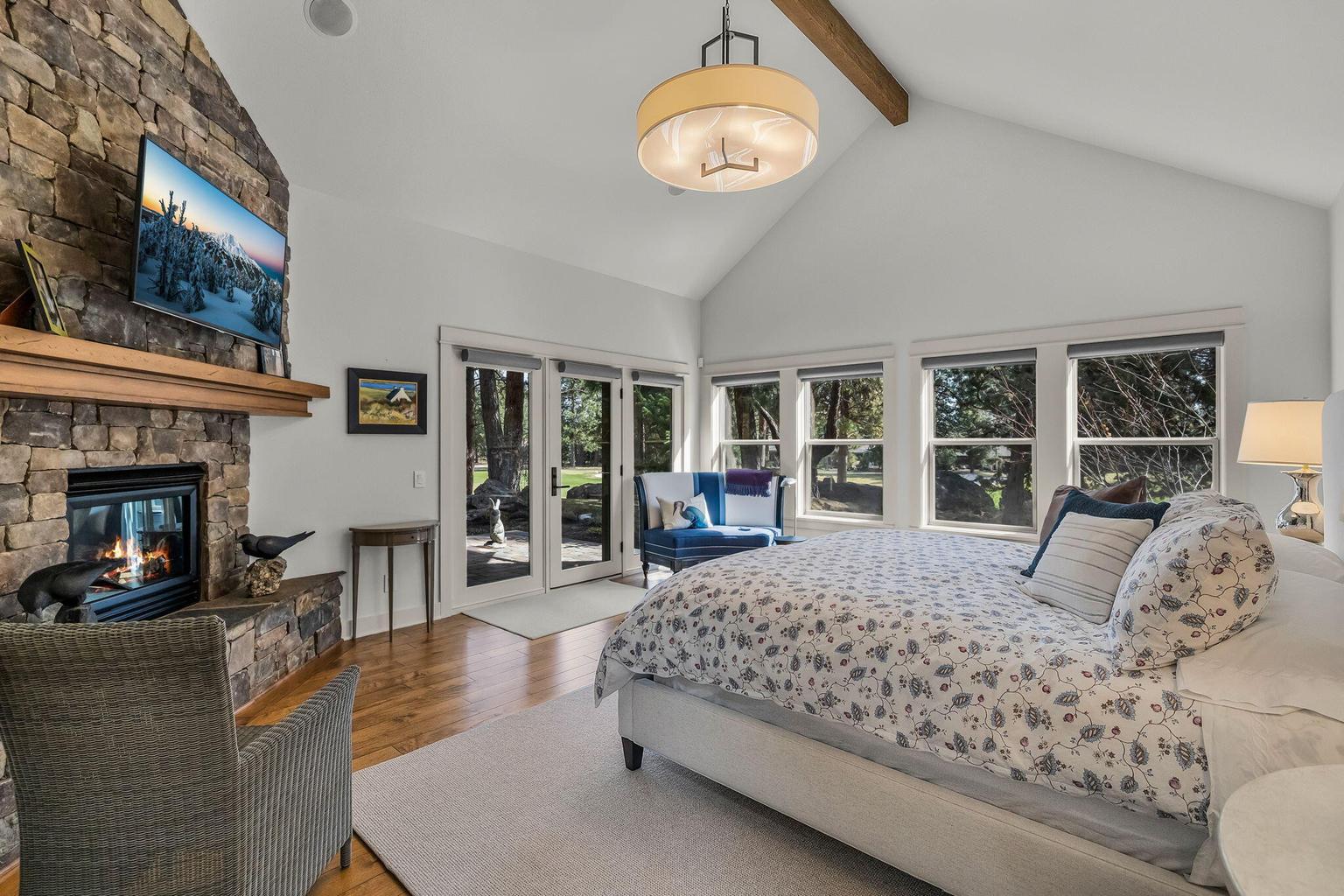 Primary suite set in a private wing, featuring a fireplace, pine and golf course views, and direct access to outdoor living with hot tub.