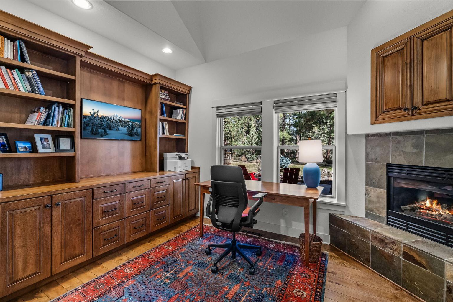 Separate office within the primary wing featuring a fireplace, custom built-ins, and views to the outdoor living areas.