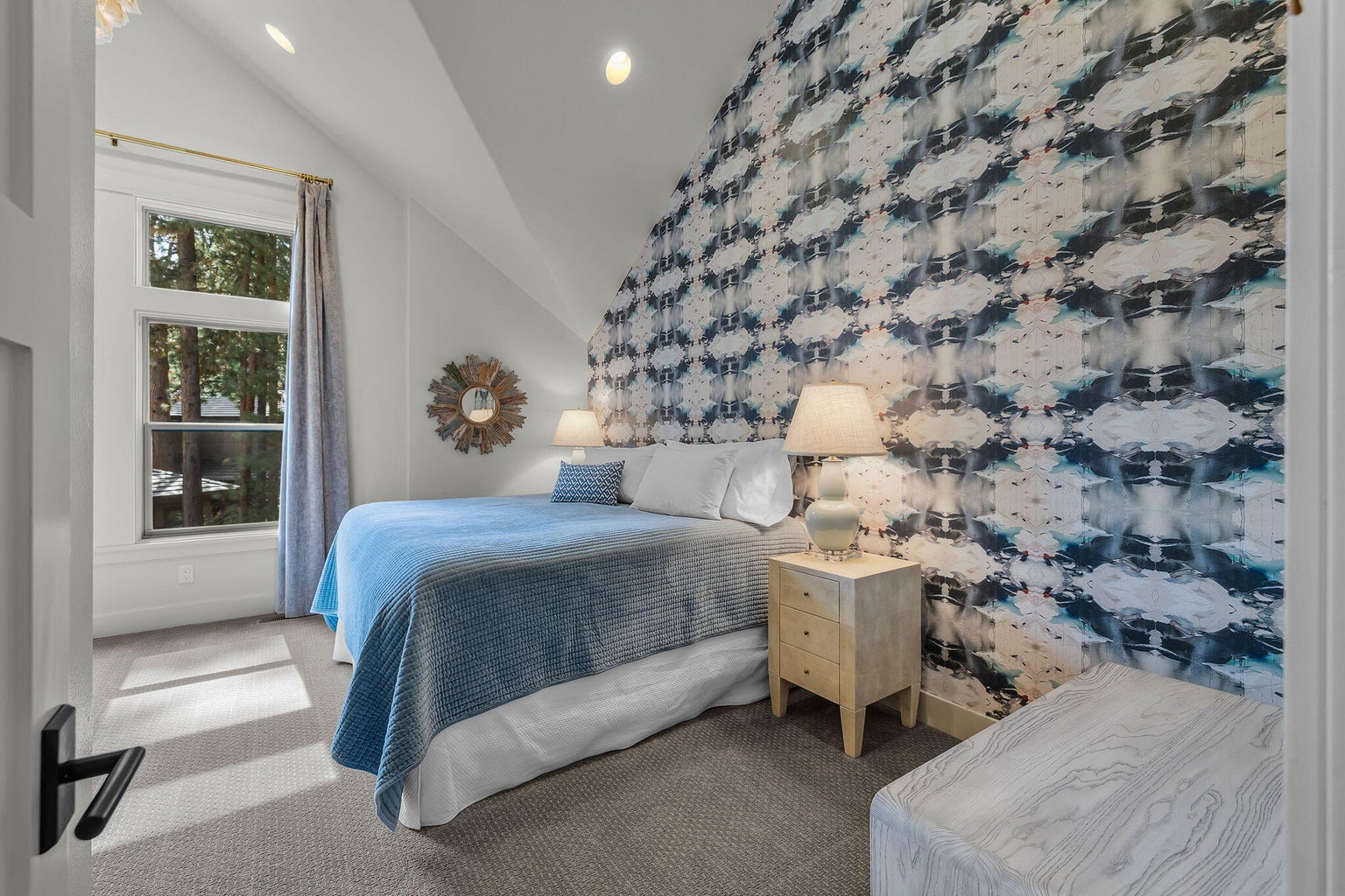 Light-filled guest bedroom within the guest wing, featuring vaulted ceiling, large windows, and a bright, comfortable feel.