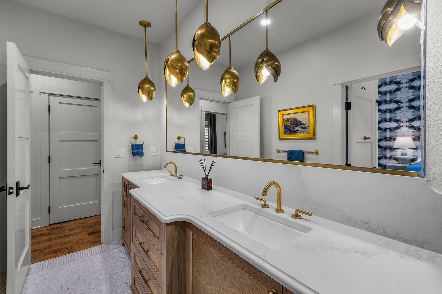 Well-appointed dual-access bath featuring separate vanities, walk-in shower, and convenient connection to both the guest bedroom and hall.