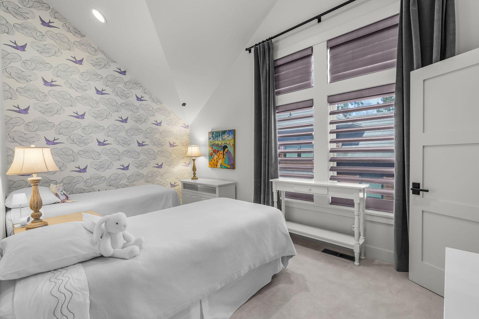 Guest bedroom within the guest wing featuring vaulted ceiling, large window, and a bright, comfortable setting.