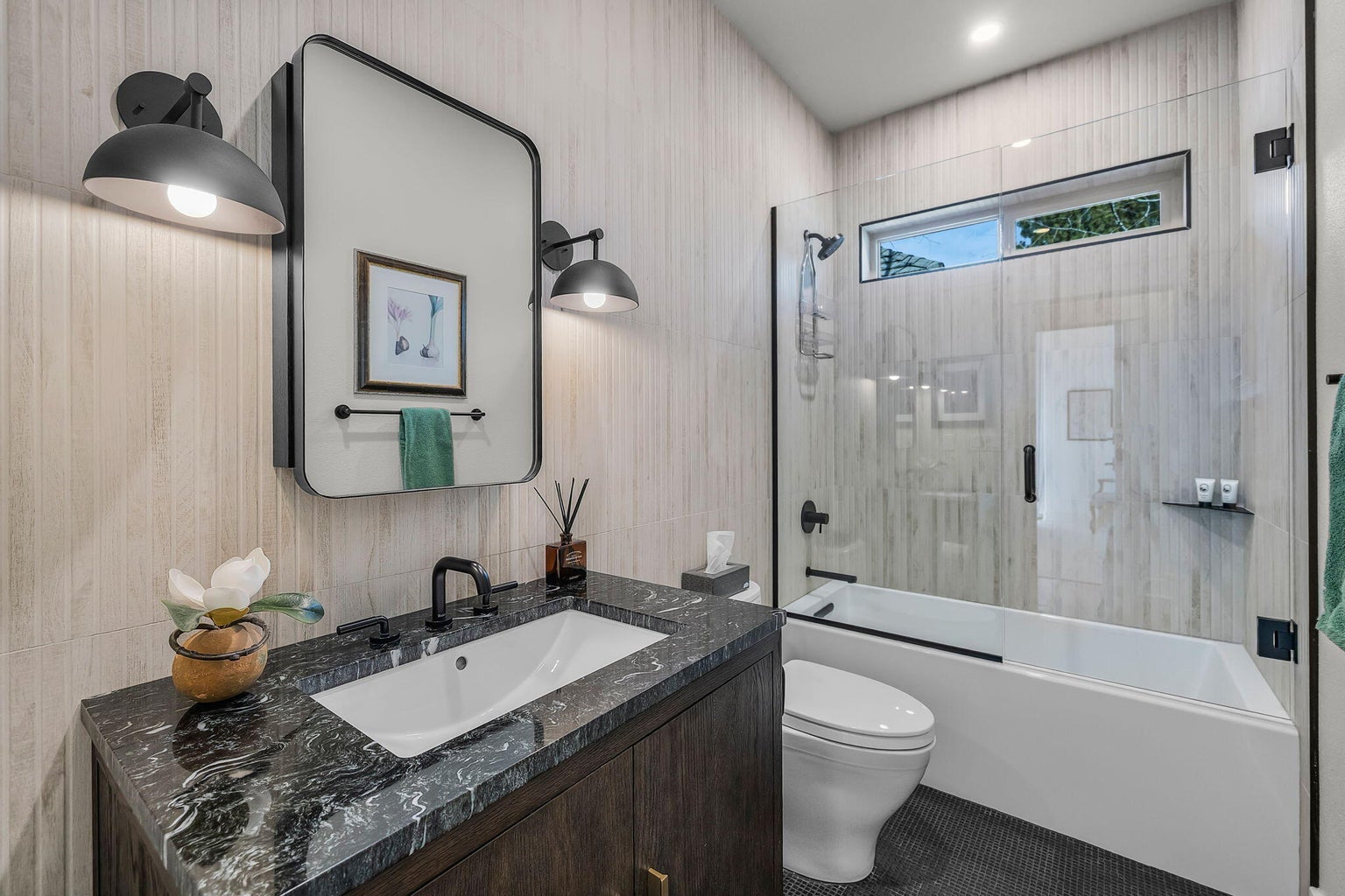 Guest bath within the guest wing featuring stone surfaces, tub/shower combination, and refined, contemporary finishes.