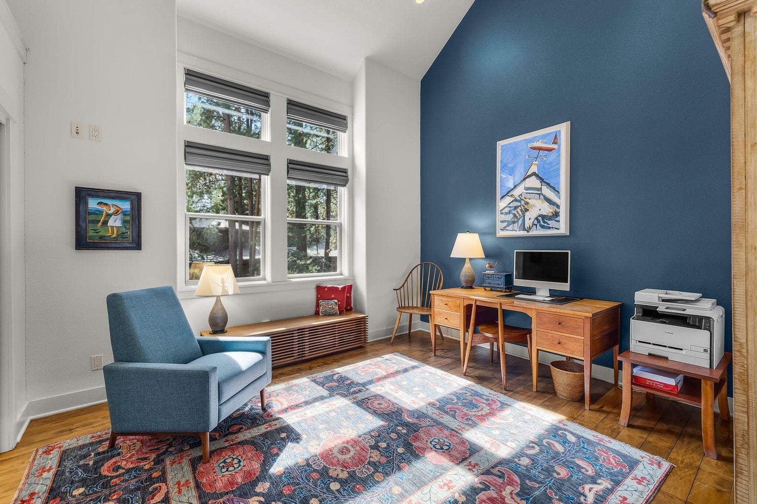 Guest bedroom within the guest wing, currently arranged as an office, featuring vaulted ceiling, large windows, and abundant natural light.