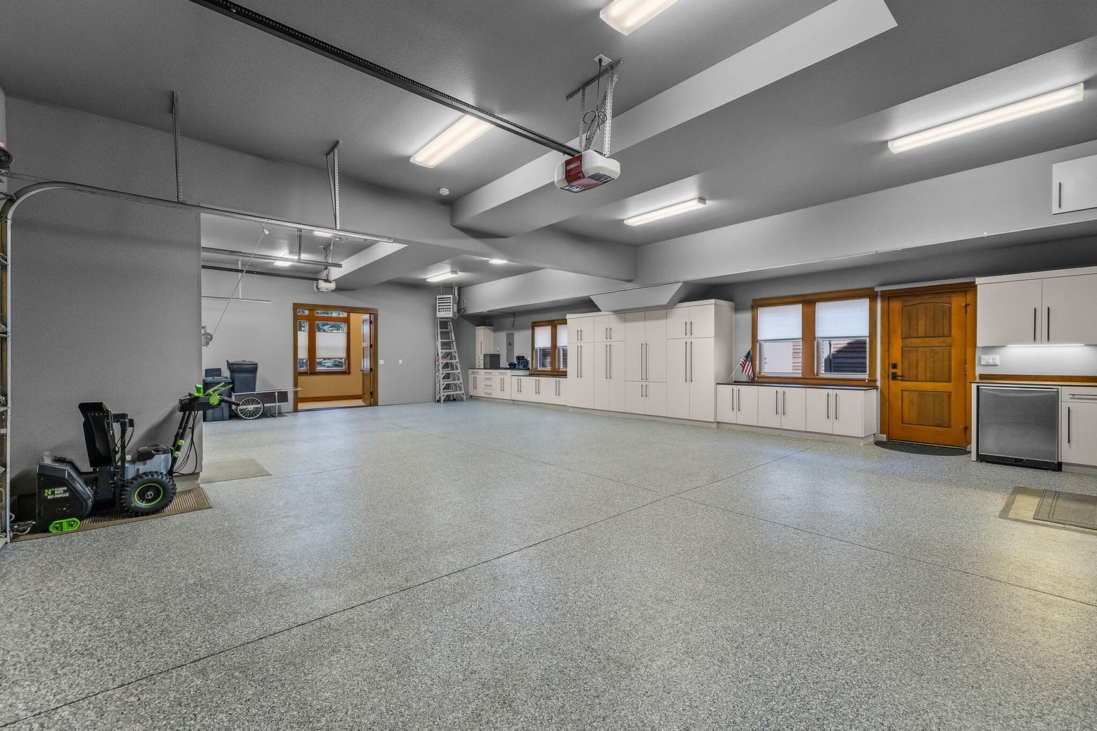 Expansive heated 4-car garage featuring epoxy floors, built-in cabinetry, and flexible space for storage, hobbies, or recreation.
