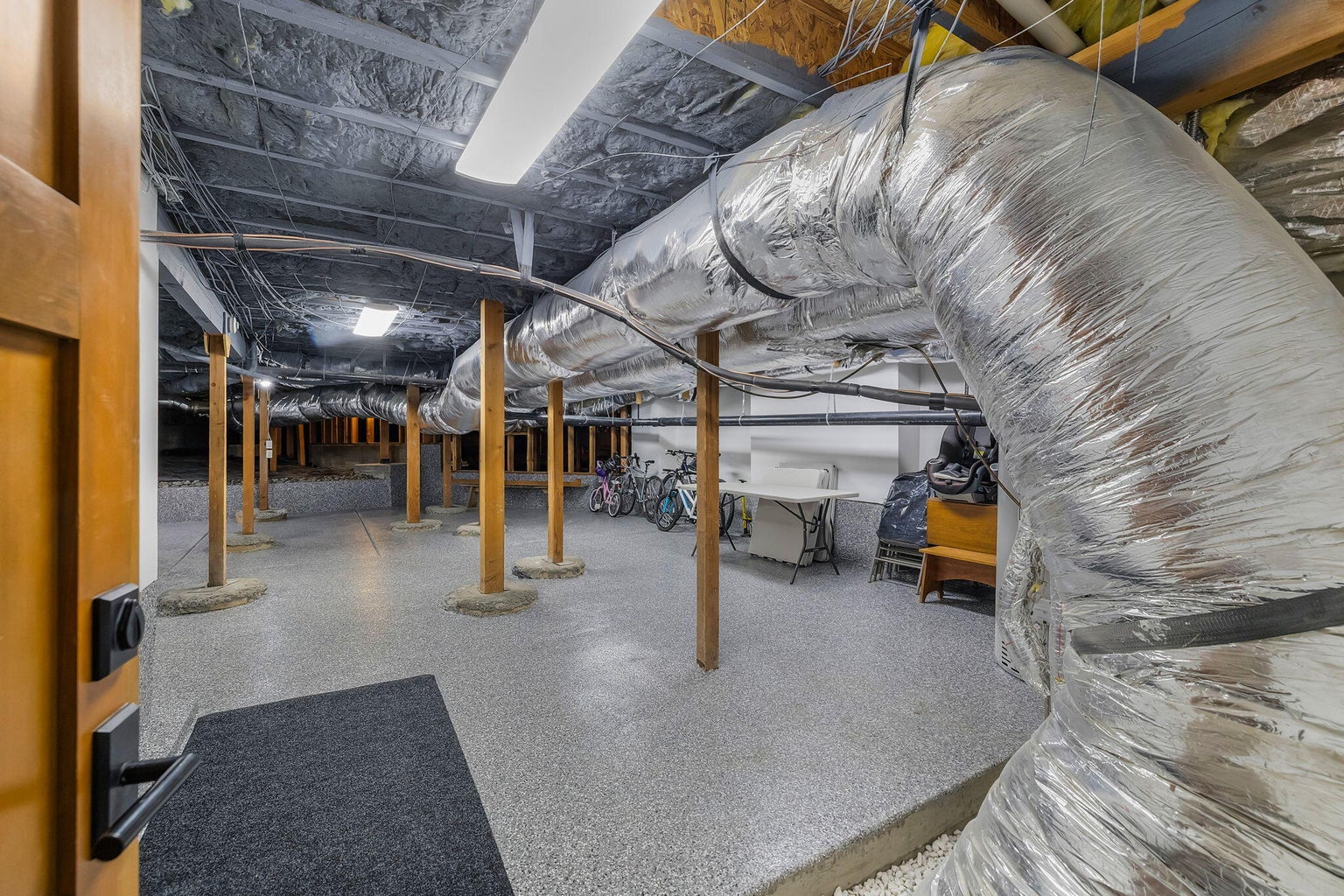 Large under-home storage and utility area with finished flooring, providing ample space for storage, hobbies, and housing major home systems.