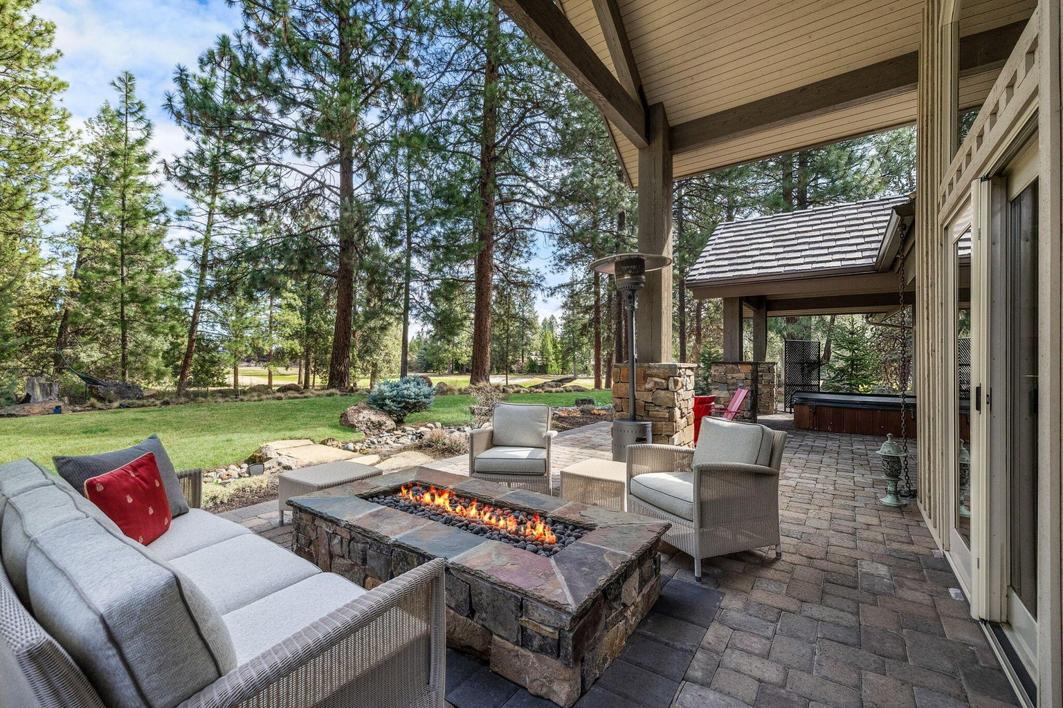 Extending from the interior living spaces, the covered patio offers a fire feature, comfortable seating, and a natural connection to the surrounding landscape.