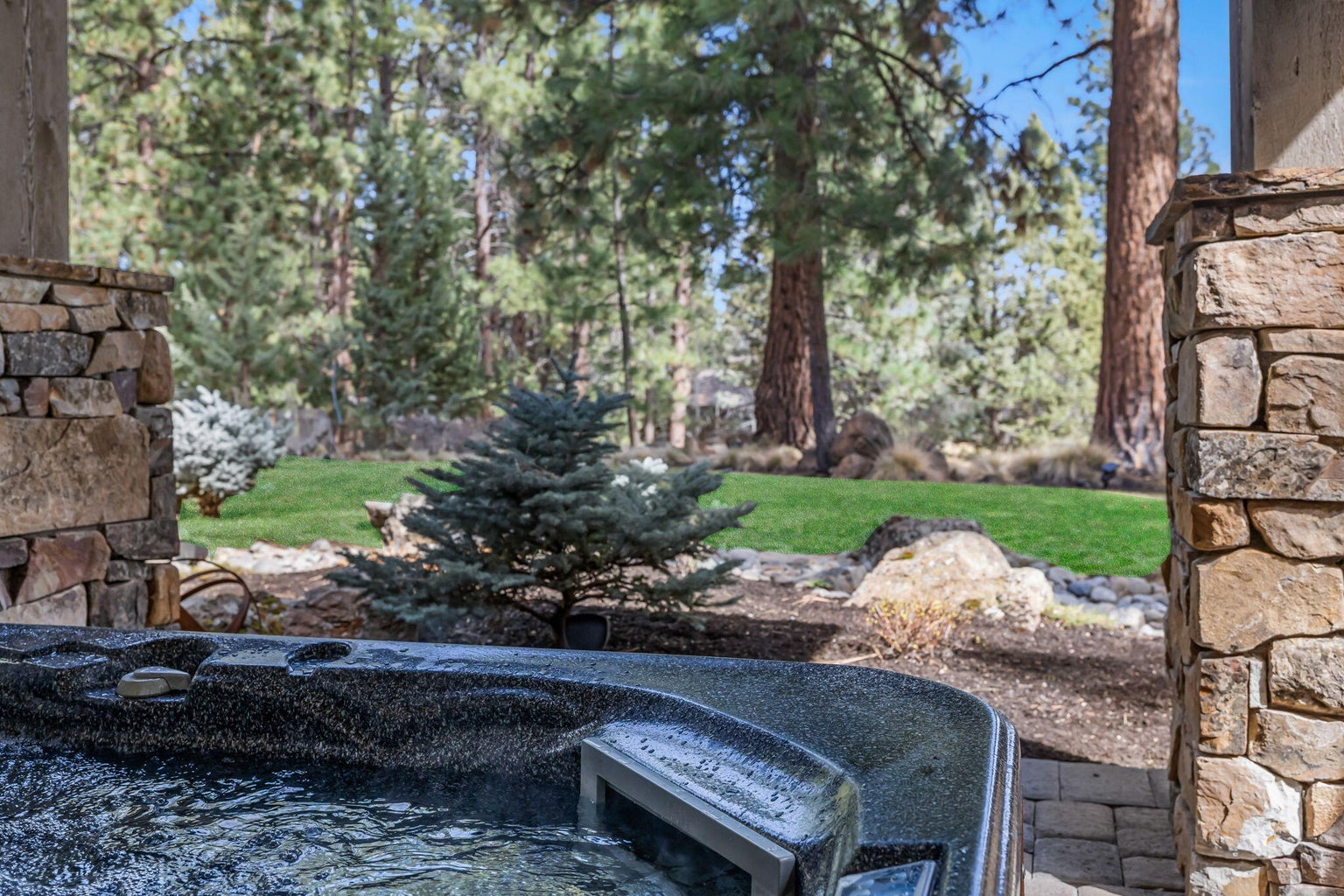 Private hot tub just off the primary suite, set within a landscaped, tree-lined setting.