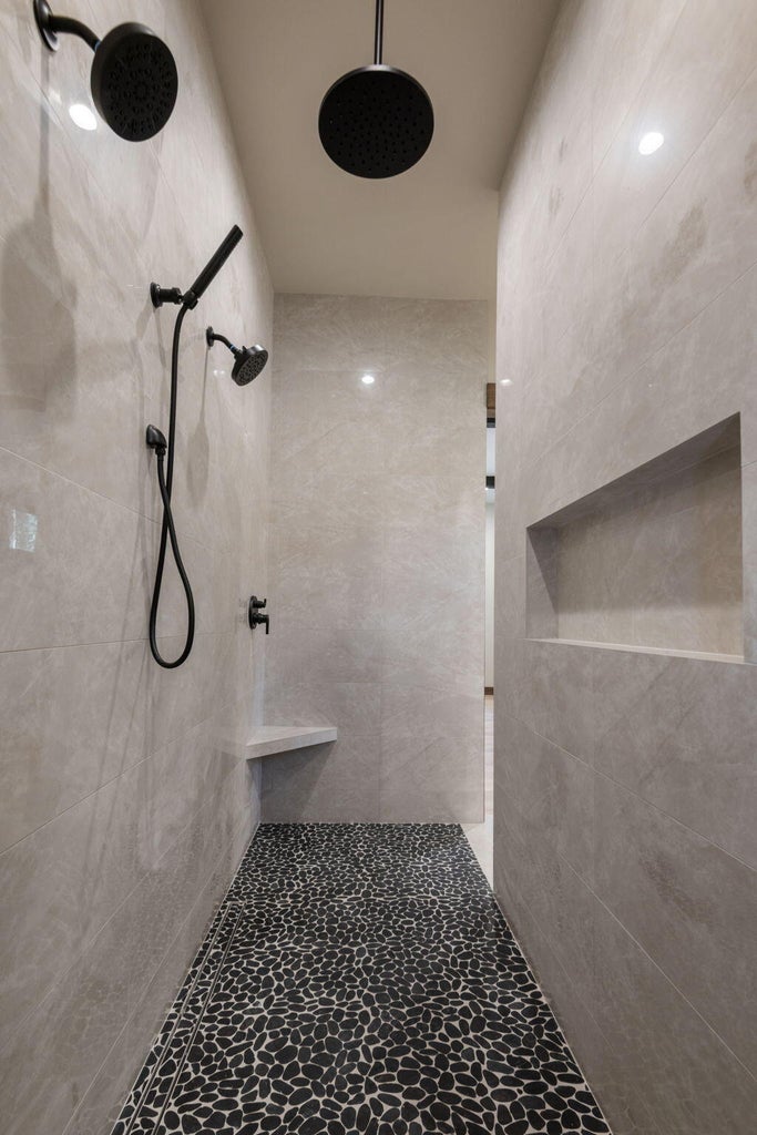 Dual-entry walk in shower with large niche cutouts and custom tiles