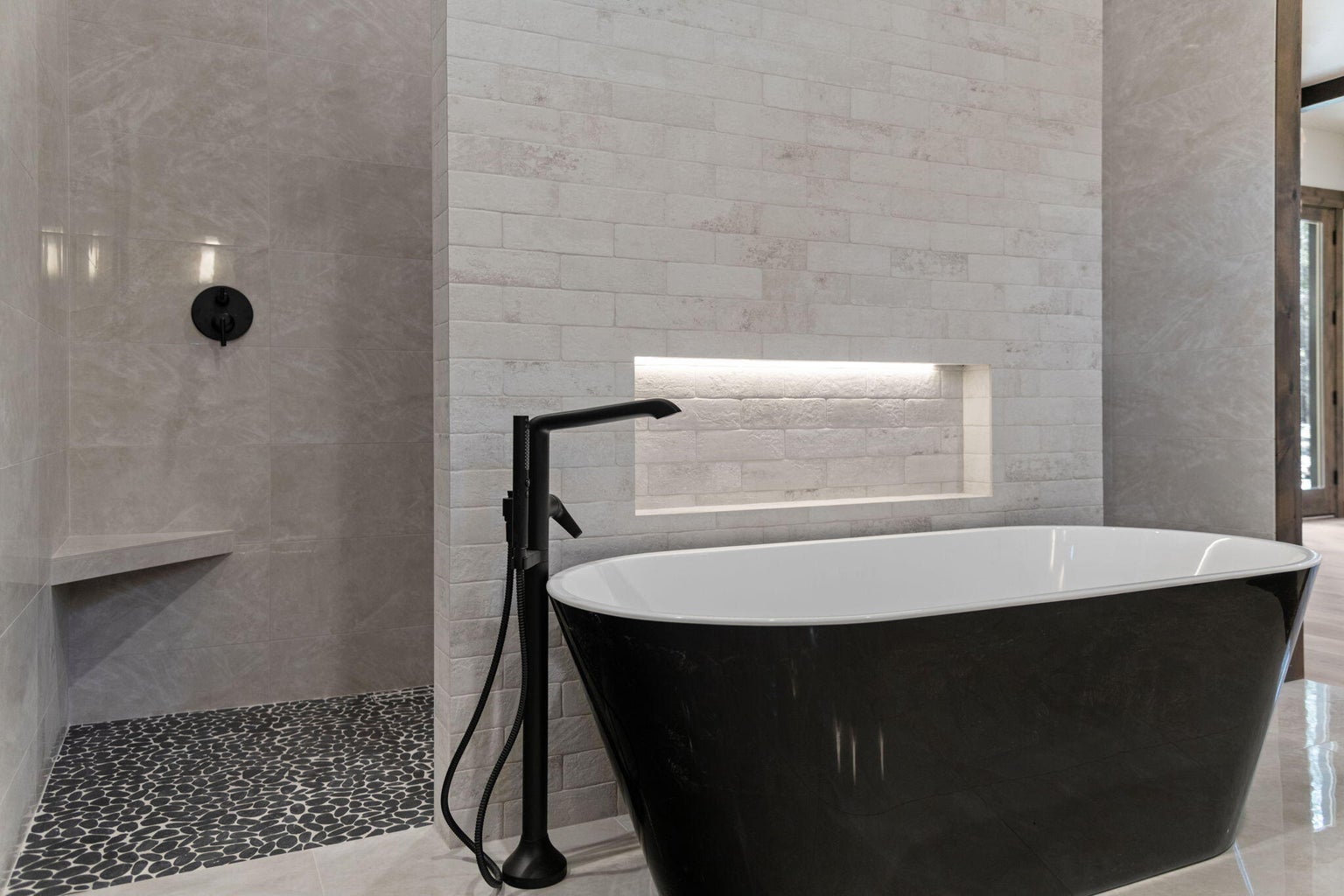 Stunning back and white bathtub with rocked up feature wall and lighted large niche above