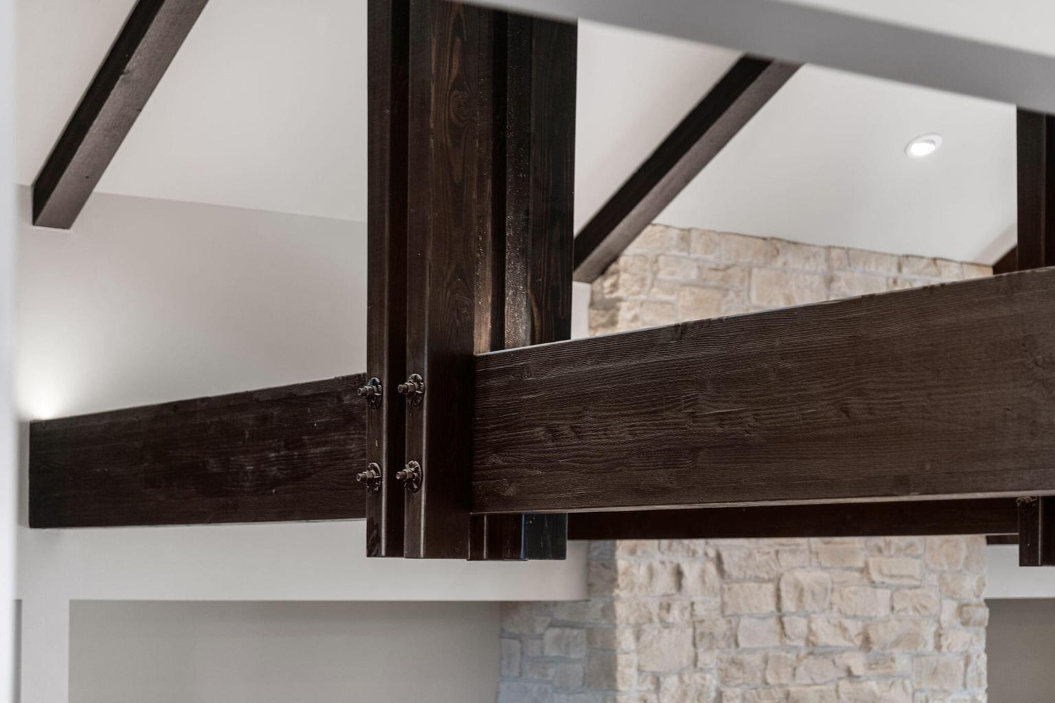Uplit custom black stained beams that extend into the kitchen