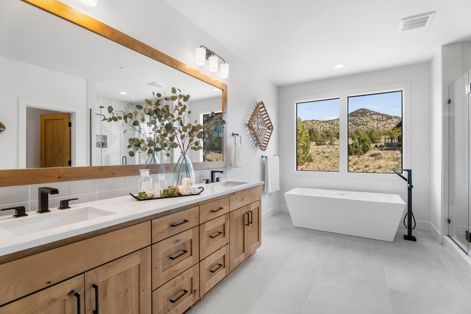 The primary bathroom with more natural light, double vanity, soaking tub, tiled walk-in shower, and water closet