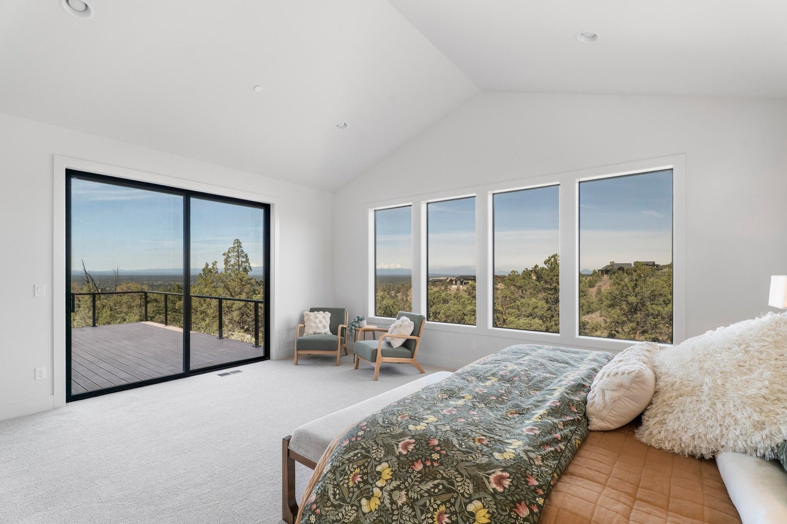 The primary suite frames Cascade Mountain views with privacy among the junipers
