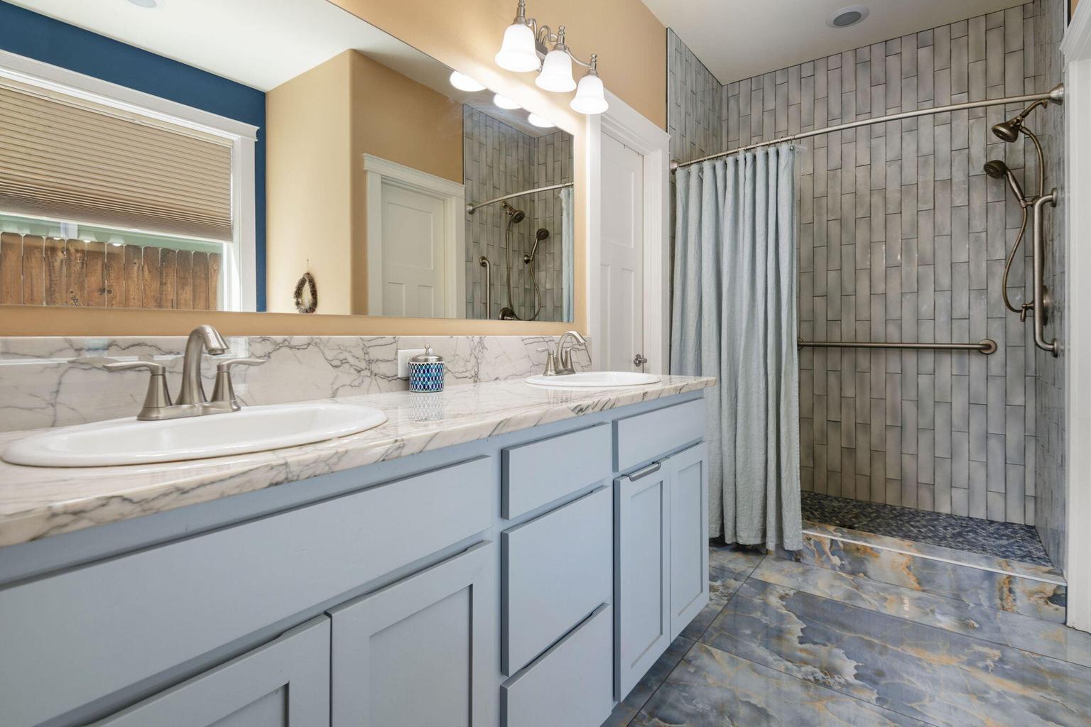 Extensively updated primary bathroom with marble floors and custom walk in shower.