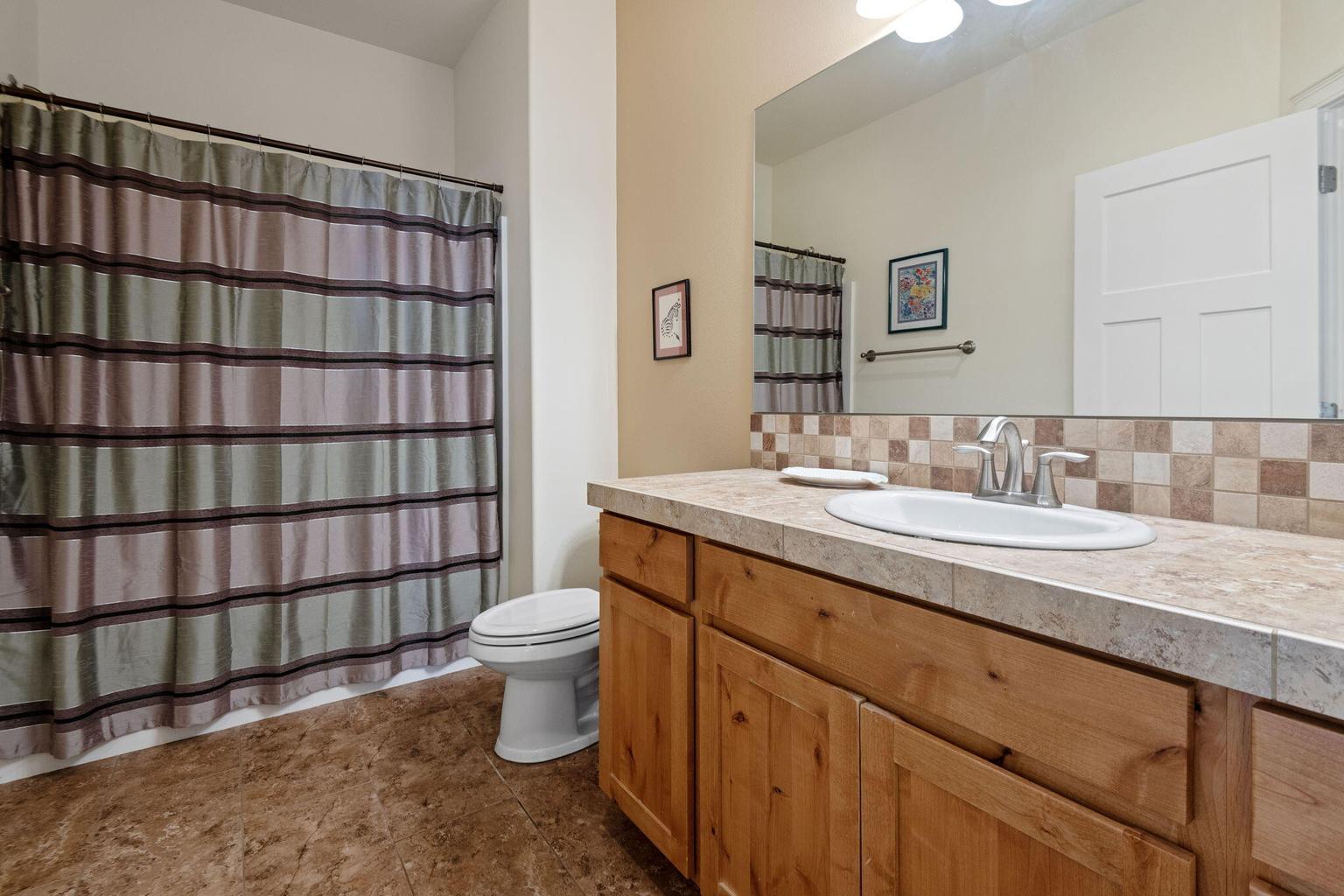 Full bathroom with tile counters, backsplash, and floors.