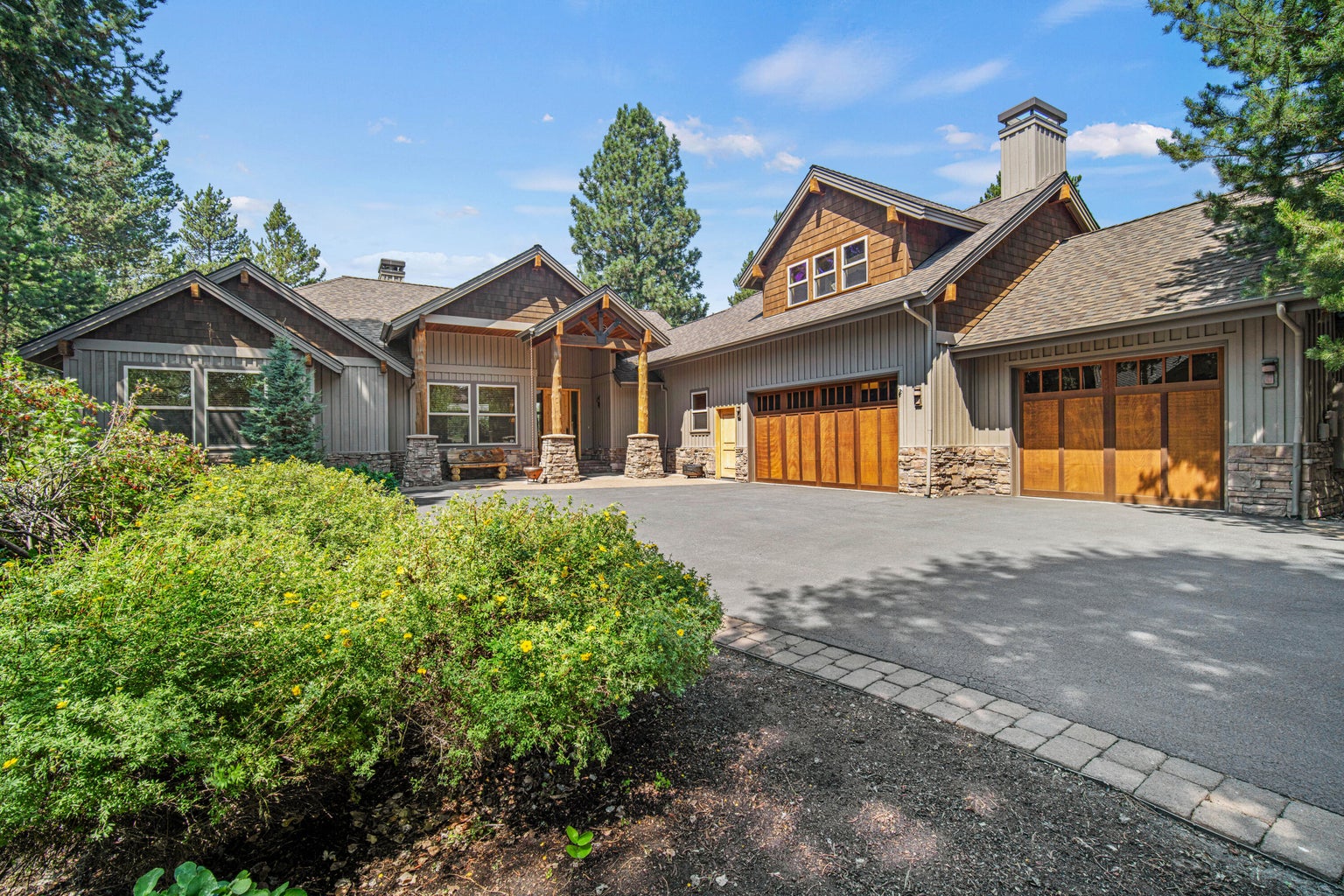 Northwest-inspired Caldera Springs exterior with stone accents, wood garage doors, mature landscaping, and a welcoming arrival experience.