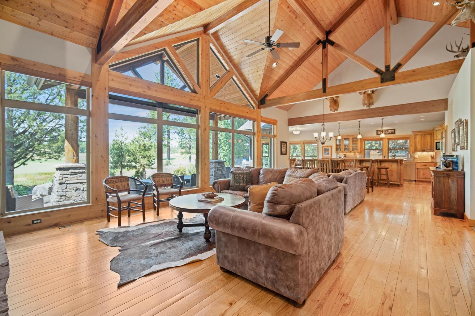Great room with soaring wood ceilings, expansive windows, and views toward the outdoor living area and the Par 5 of the Caldera Springs Links golf setting.