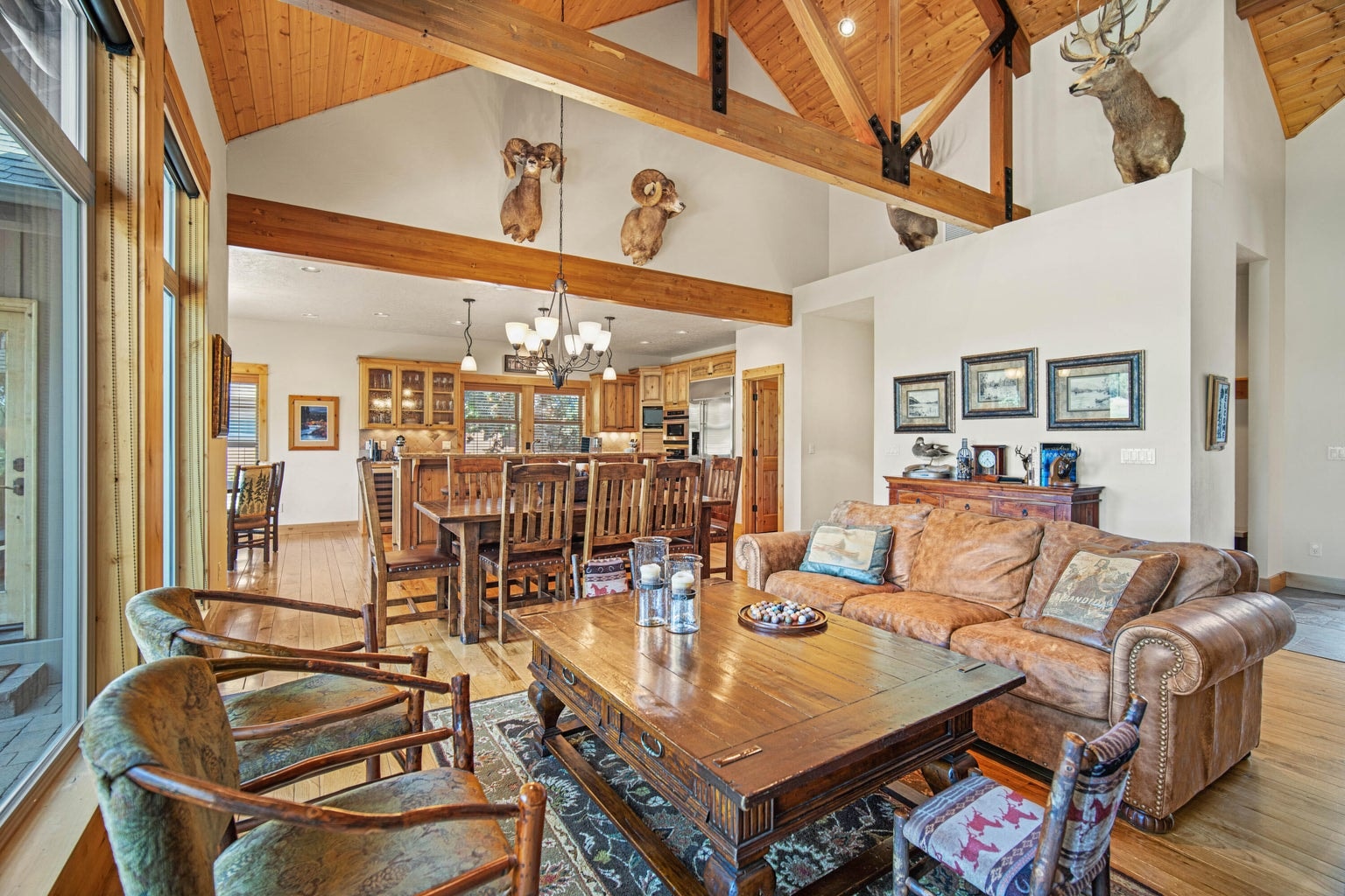 Open-truss design connects the great room, dining area, and kitchen with warm wood finishes and natural light.