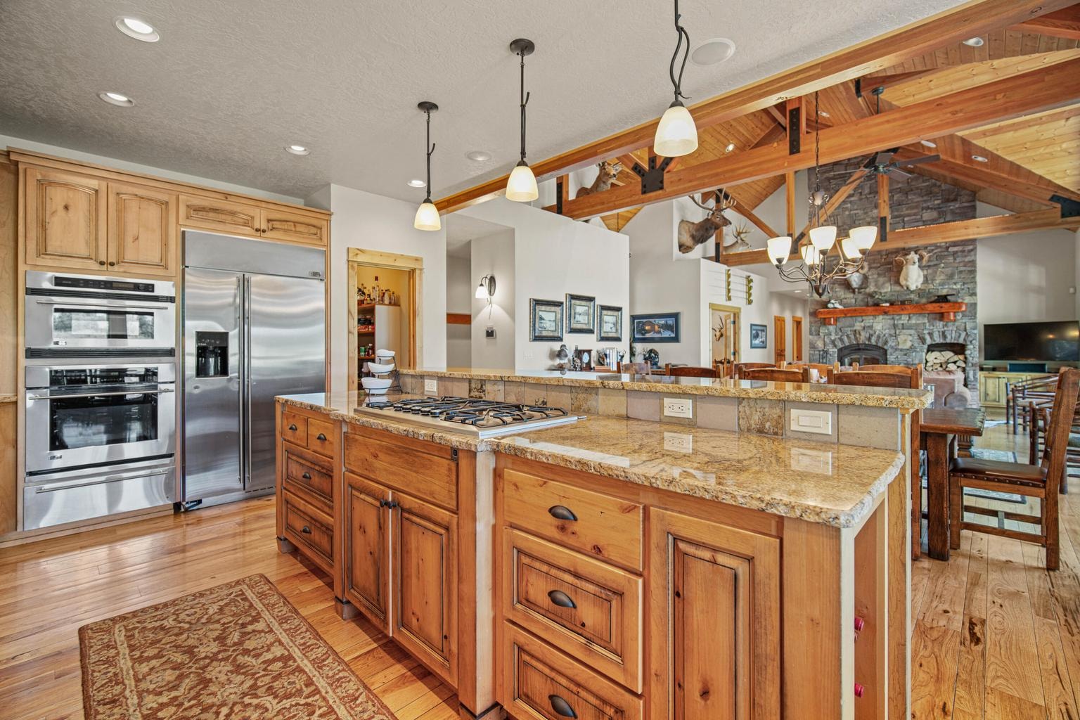 Granite island, gas cooktop, custom cabinetry, and open sightlines to the great room and fireplace.
