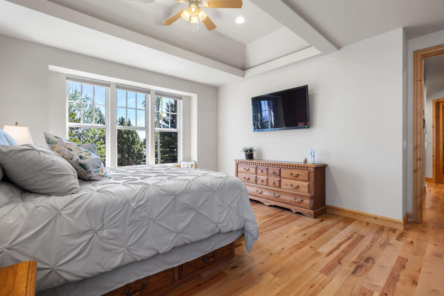 Primary bedroom has ceiling fan and beautiful wood floors