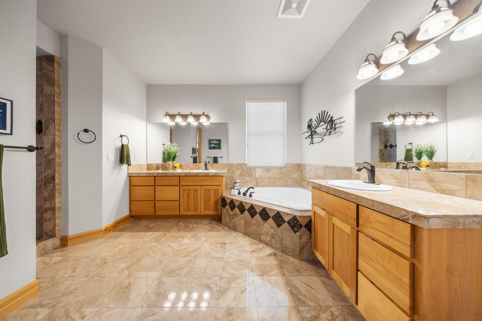 Primary Bathroom with dual vanities, whirlpool tub and marble tile finishes