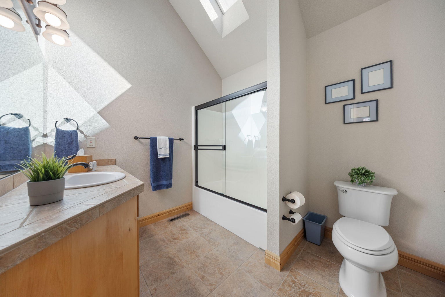Full bath upstairs has vaulted ceiling and skylight with solar shade