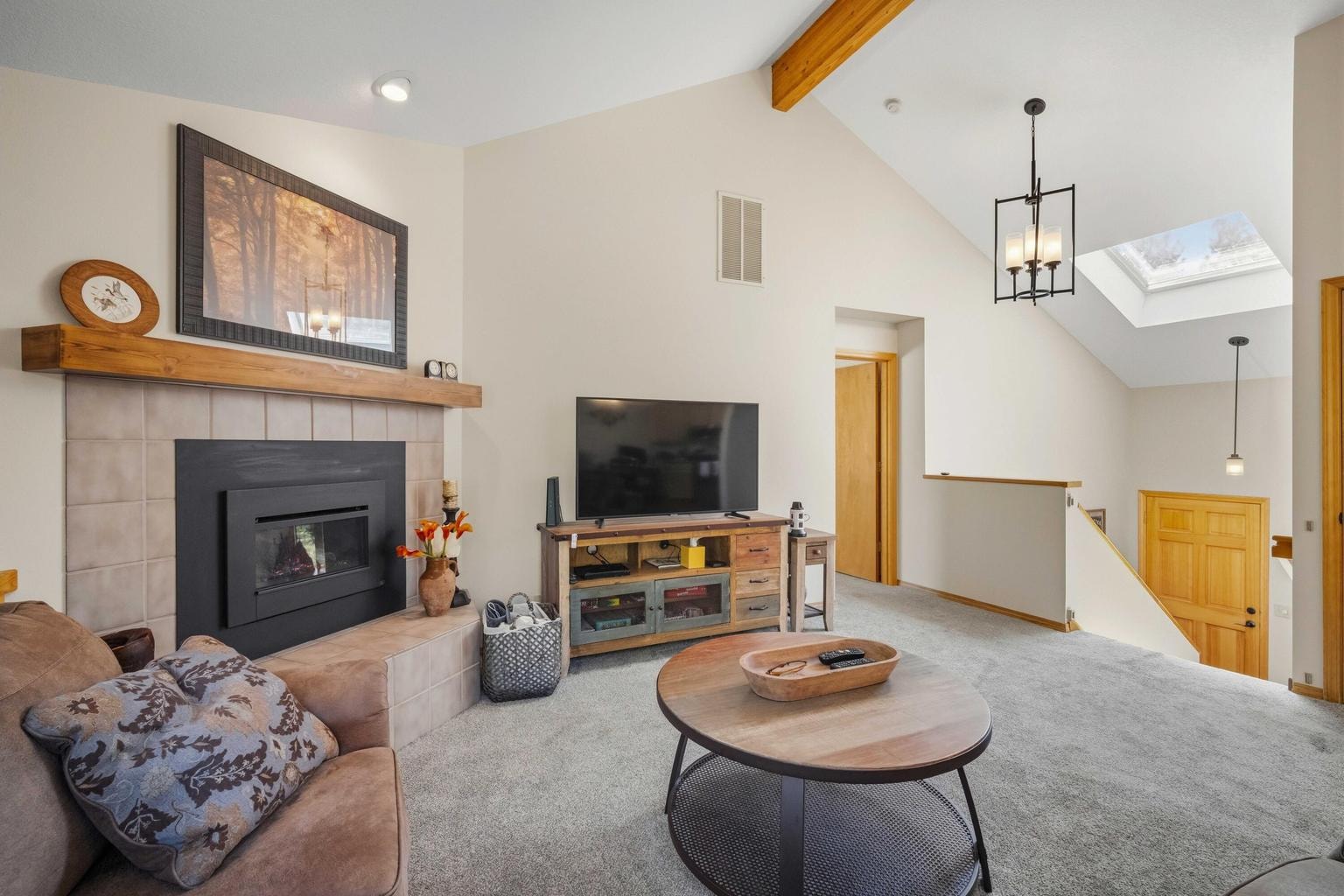 Vaulted great room with gas fireplace, new mantel, skylight, and open connection to the entry and dining area.