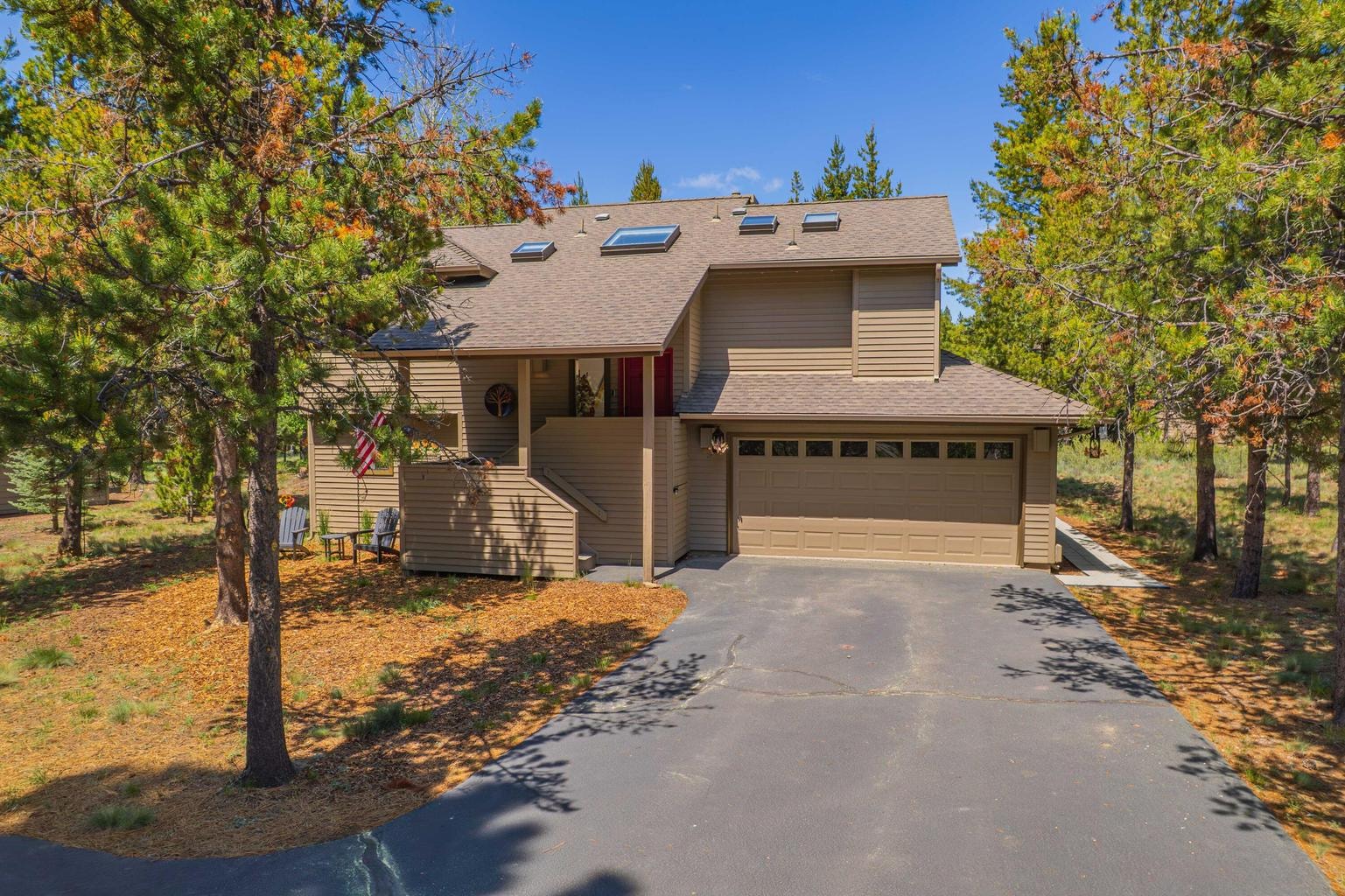 Welcoming Sunriver exterior with skylights, attached garage, and lightly treed surroundings.