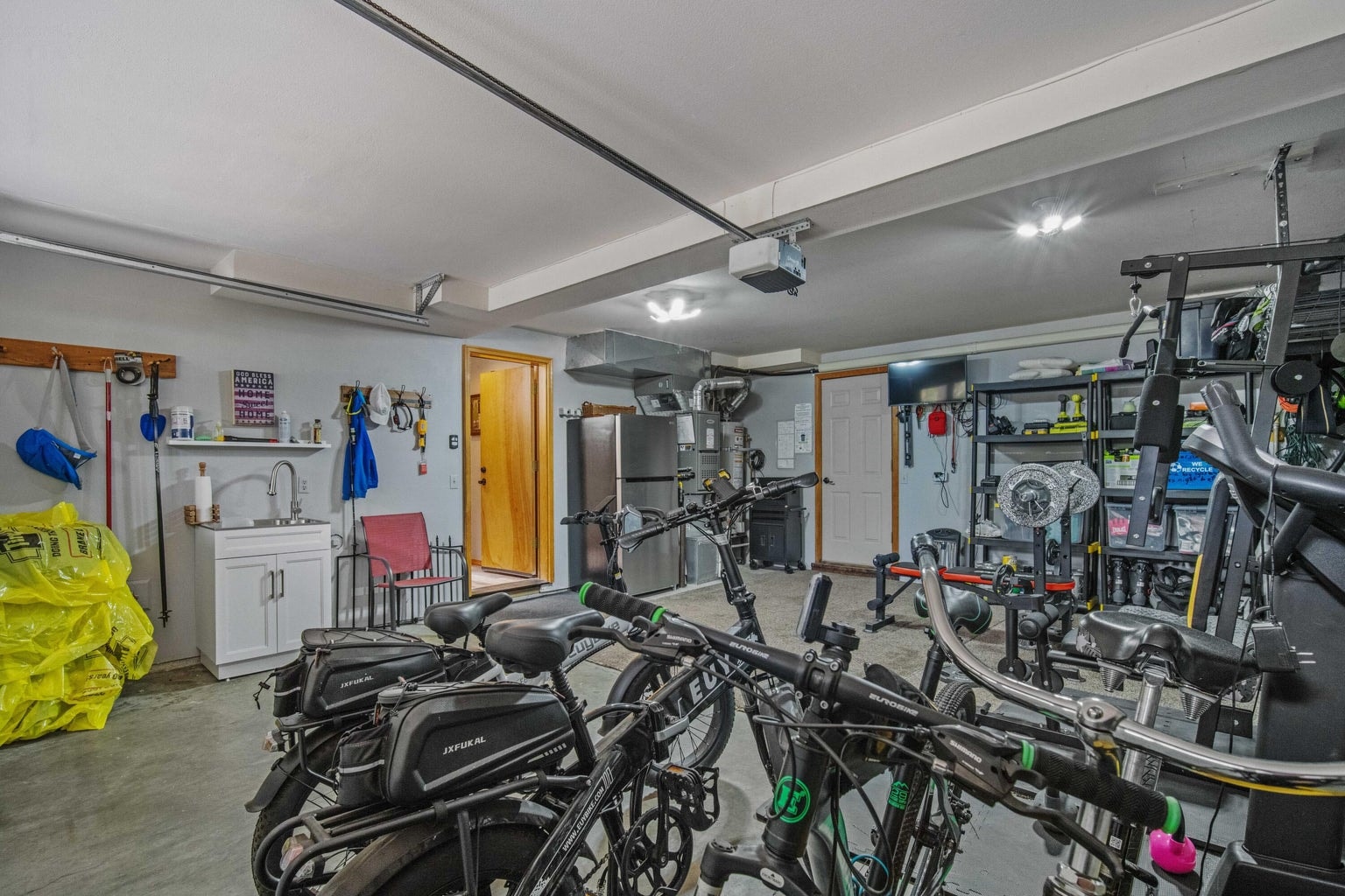 Garage utility area with added sink, storage, and space for bikes and tools.