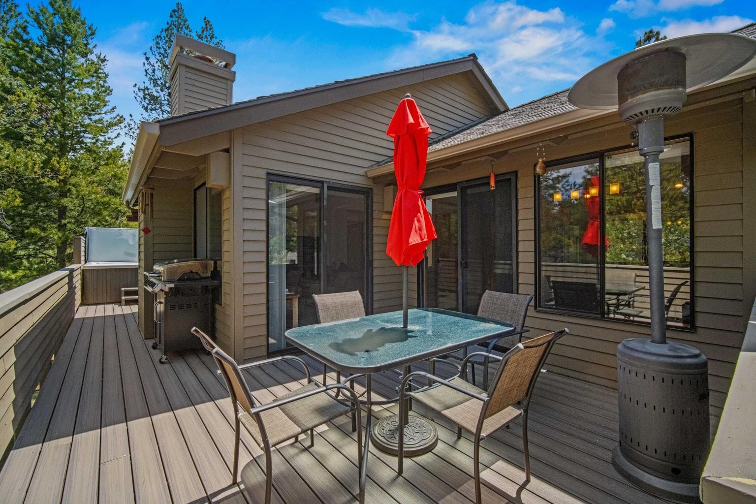 Updated Trex deck with dining area, grill zone, heater, and hot tub access.