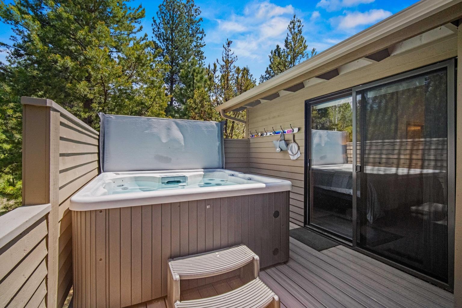Private hot tub tucked along the upper deck with surrounding pine views.