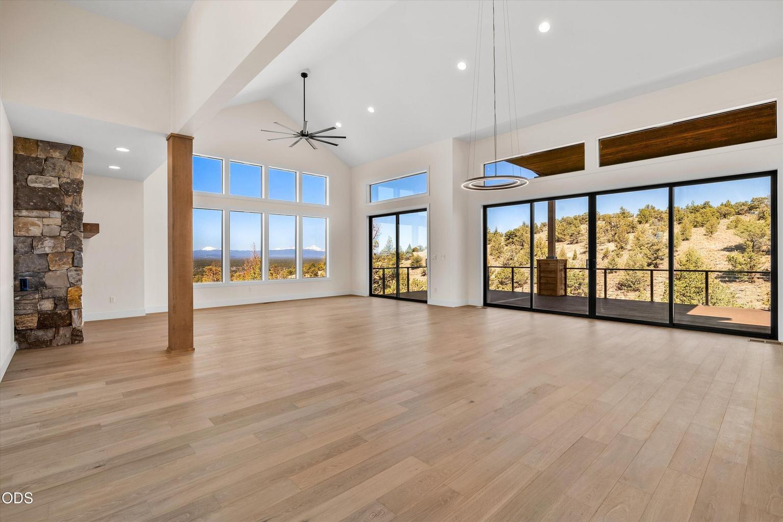 Great room featuring a wall of sliding glass doors, vaulted ceilings, modern fan and dining area fixtures, gas fireplace
