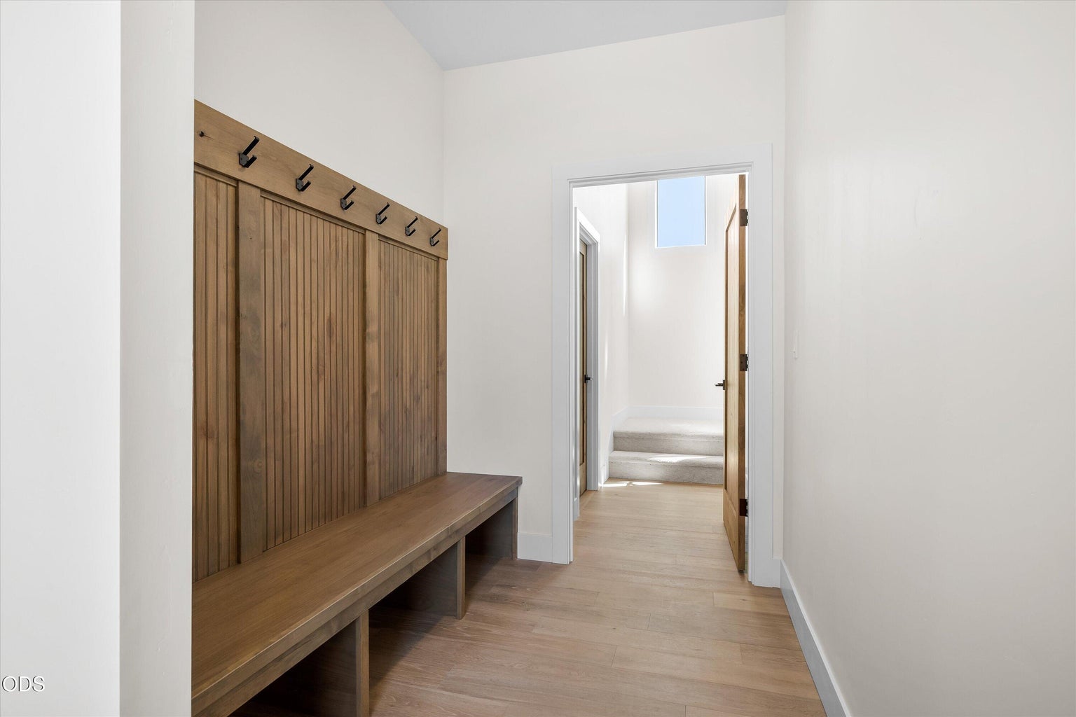 This part of the hallway functions as a mud room with storage bench and hooks, connecting the garage and bonus room to the bedrooms and great room