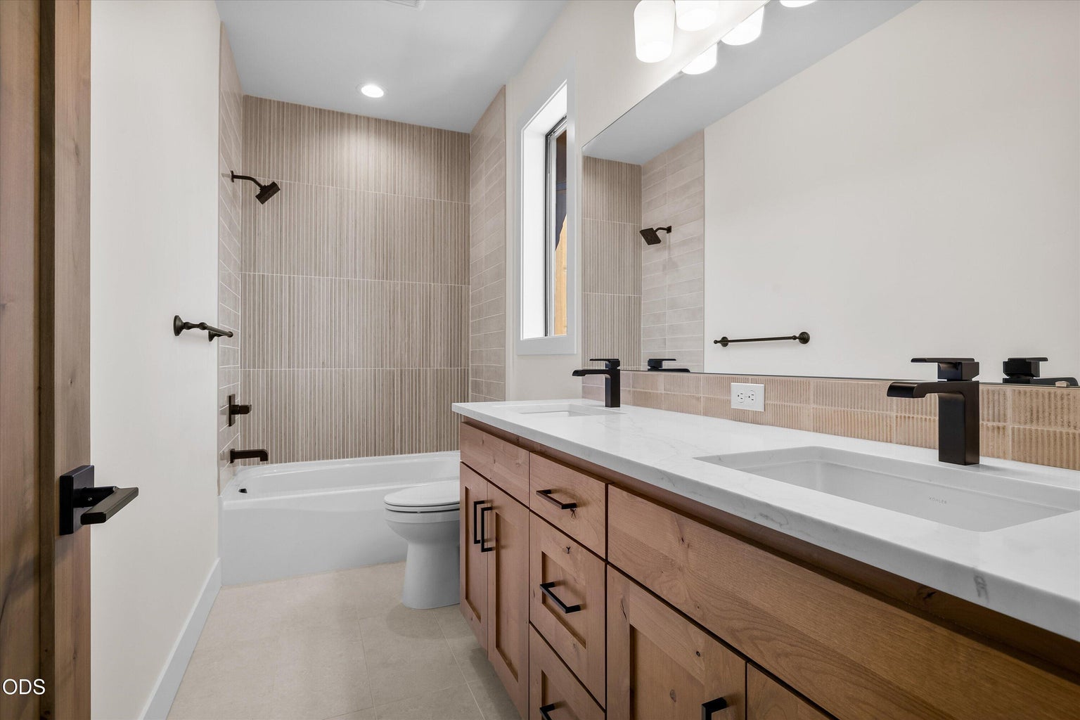 Bathroom on the primary level featuring double vanity and a bathtub shower combo, at the bottom of the stairs leading up tho the bonus room.