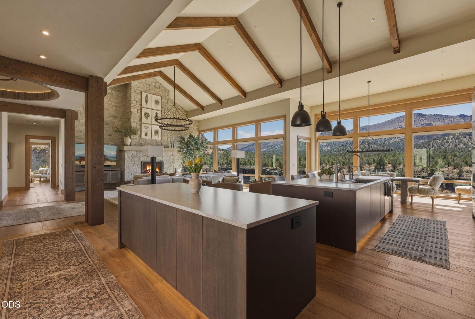 Living room looking toward kitchen, wood beam cathedral ceiling, outdoor dining and canyon visible