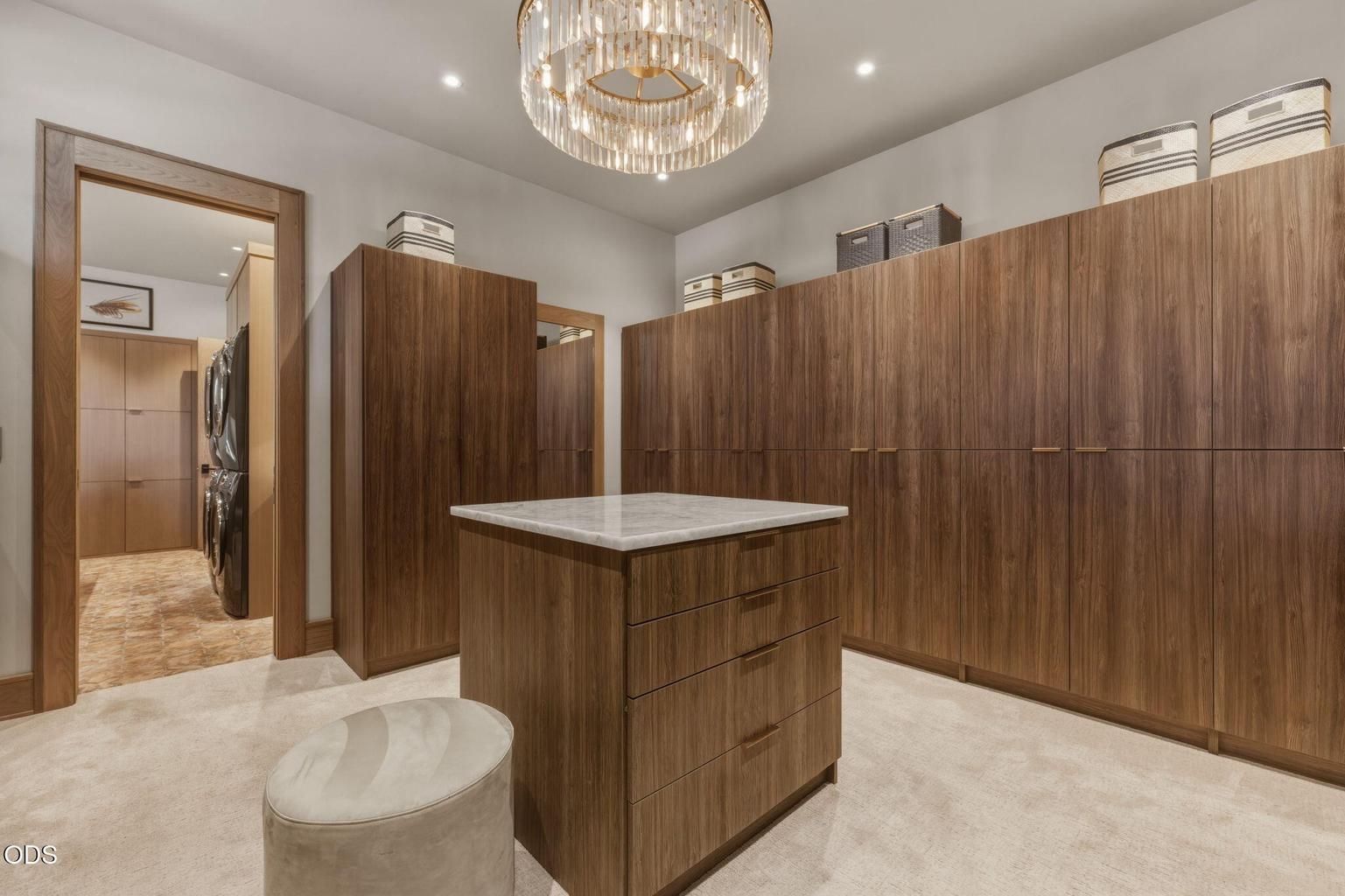 Primary walk-in closet, custom walnut cabinetry, lighted center island, laundry adjacent