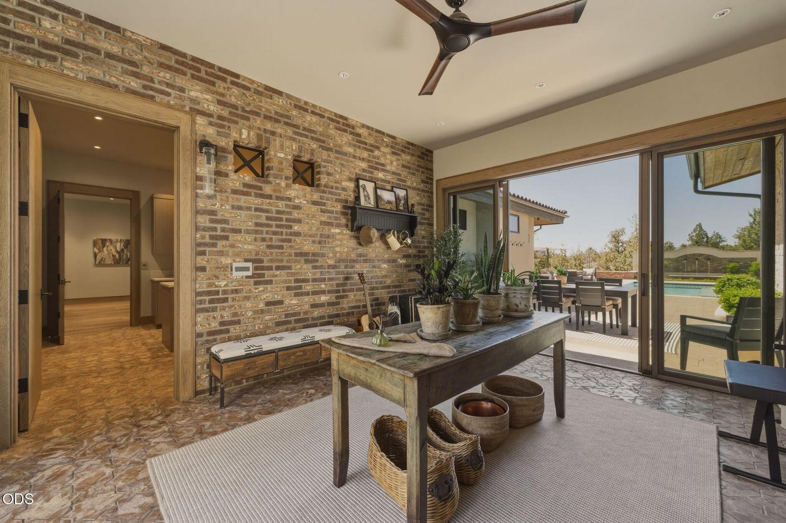 Transitional space, brick walls, slider to outdoor dining and pool