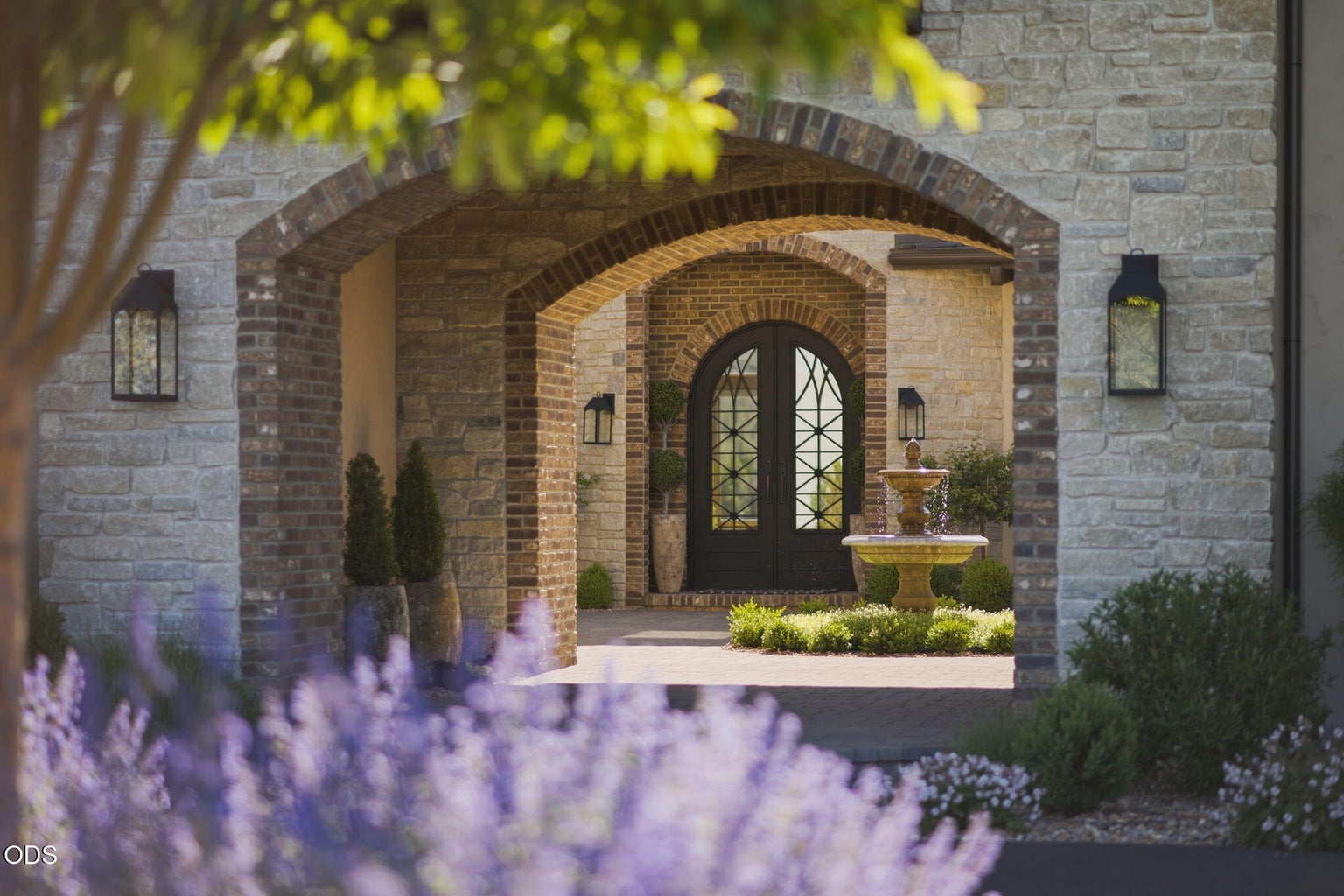 Entry courtyard through arch, iron double doors, stone fountain