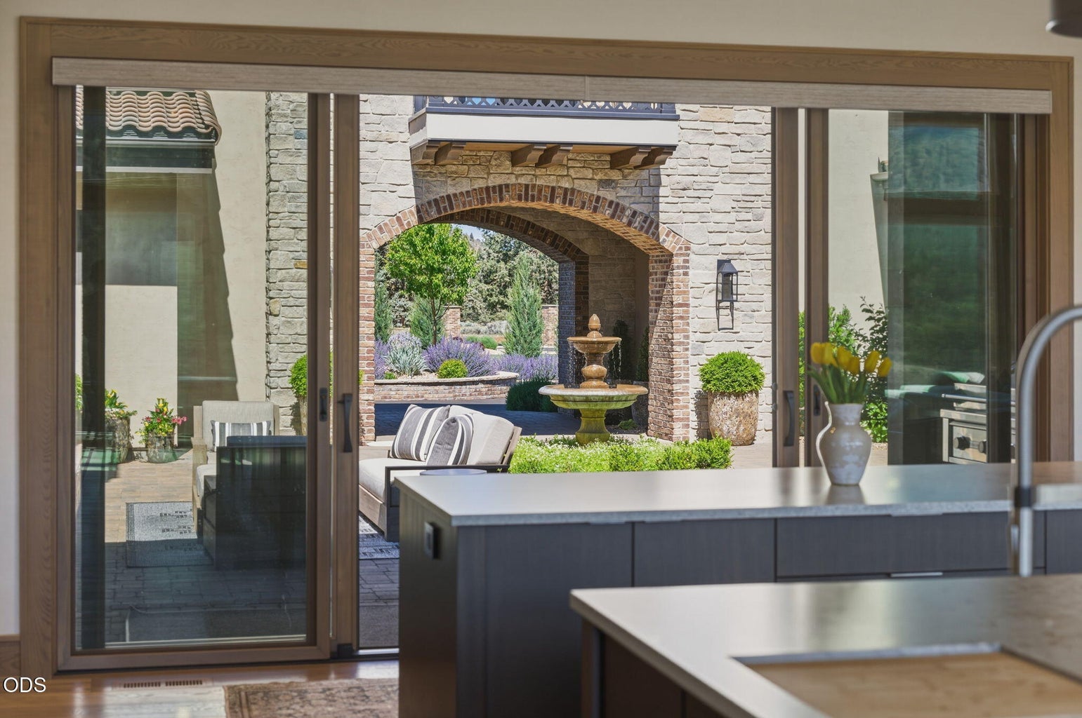 Kitchen looking out through sliders to courtyard fountain and arched passageway