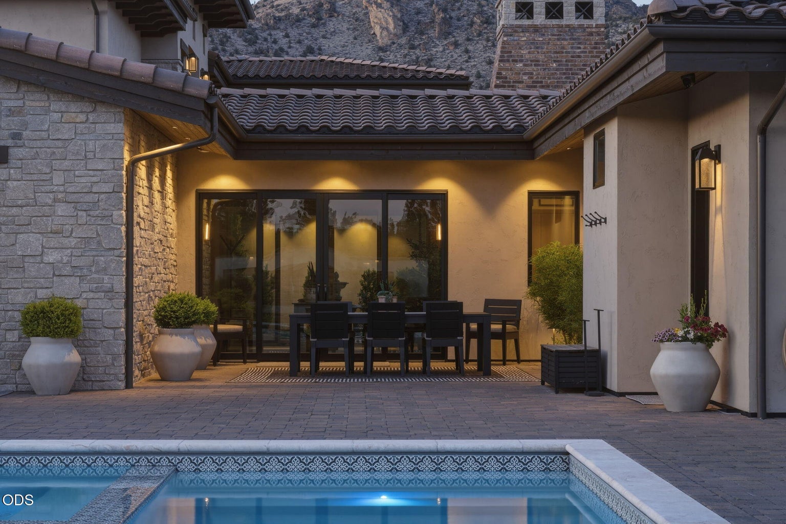 Outdoor dining terrace at dusk, pool, canyon ridgeline above