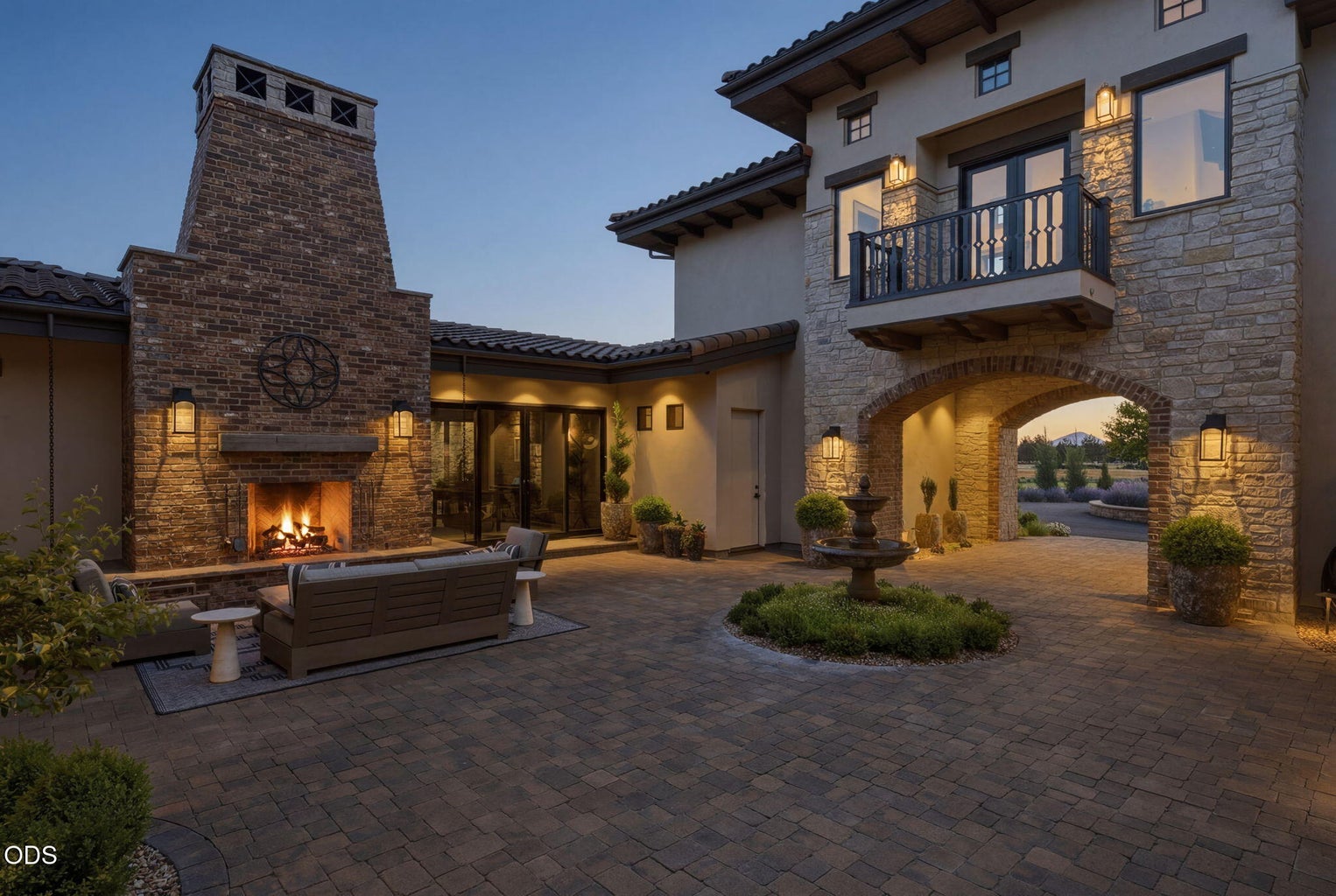 Courtyard at dusk, outdoor fireplace, stone fountain, upper balcony