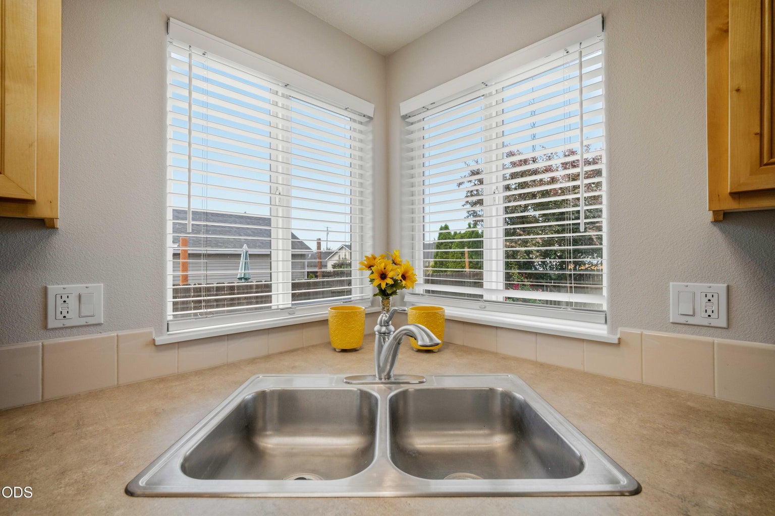 Corner windows above the kitchen sink bring in cheerful natural light and create a bright place for daily routines.