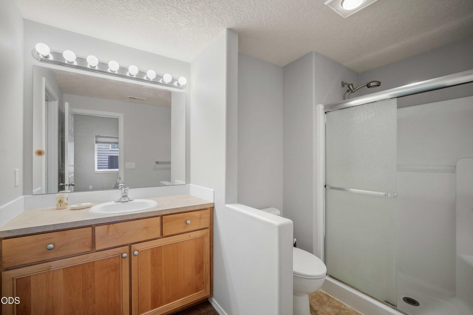 The en suite bath features a bright vanity area, good lighting, and easy-care finishes for daily convenience.