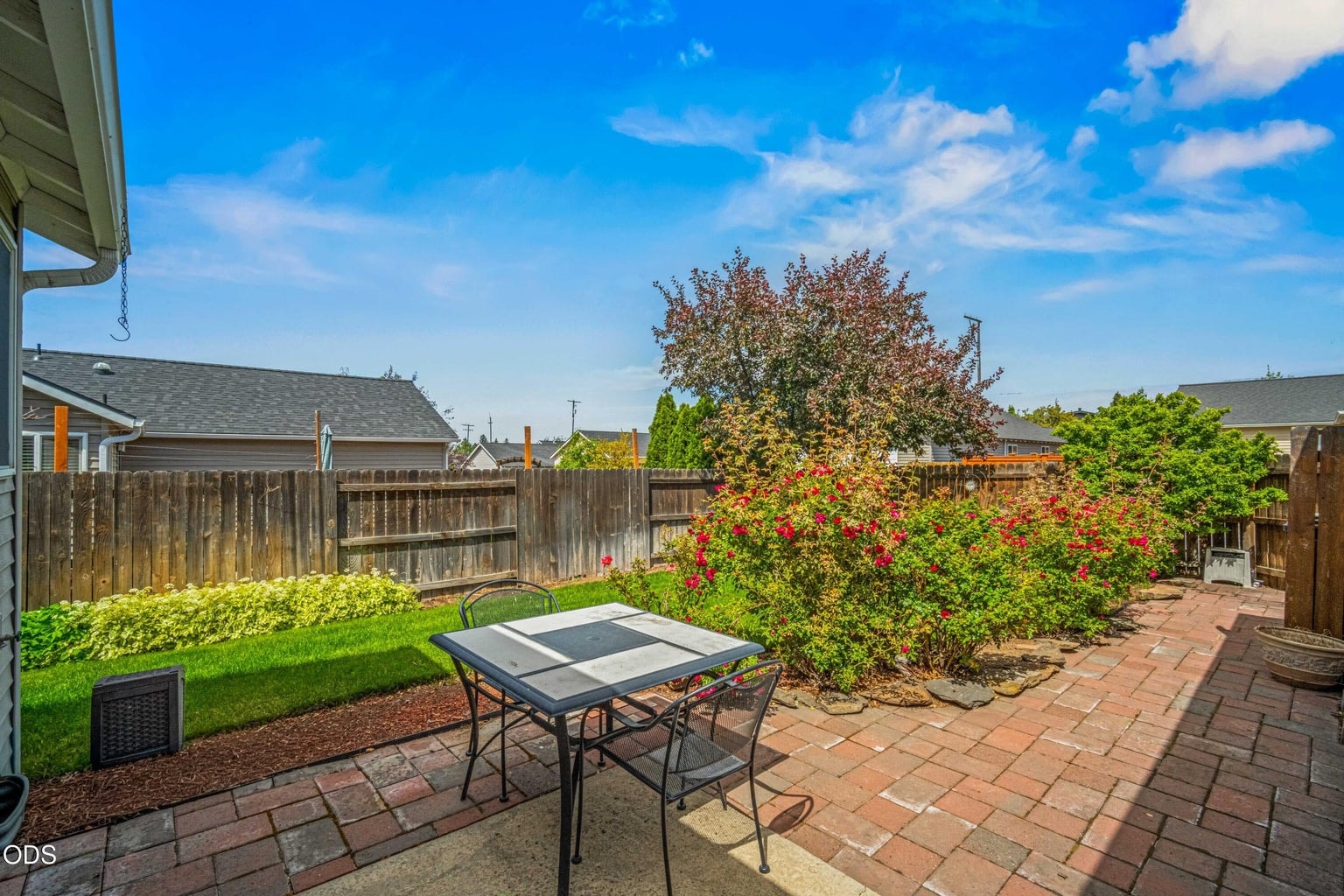 The fenced backyard patio creates an inviting setting for outdoor dining, morning coffee, or summer evenings at home.