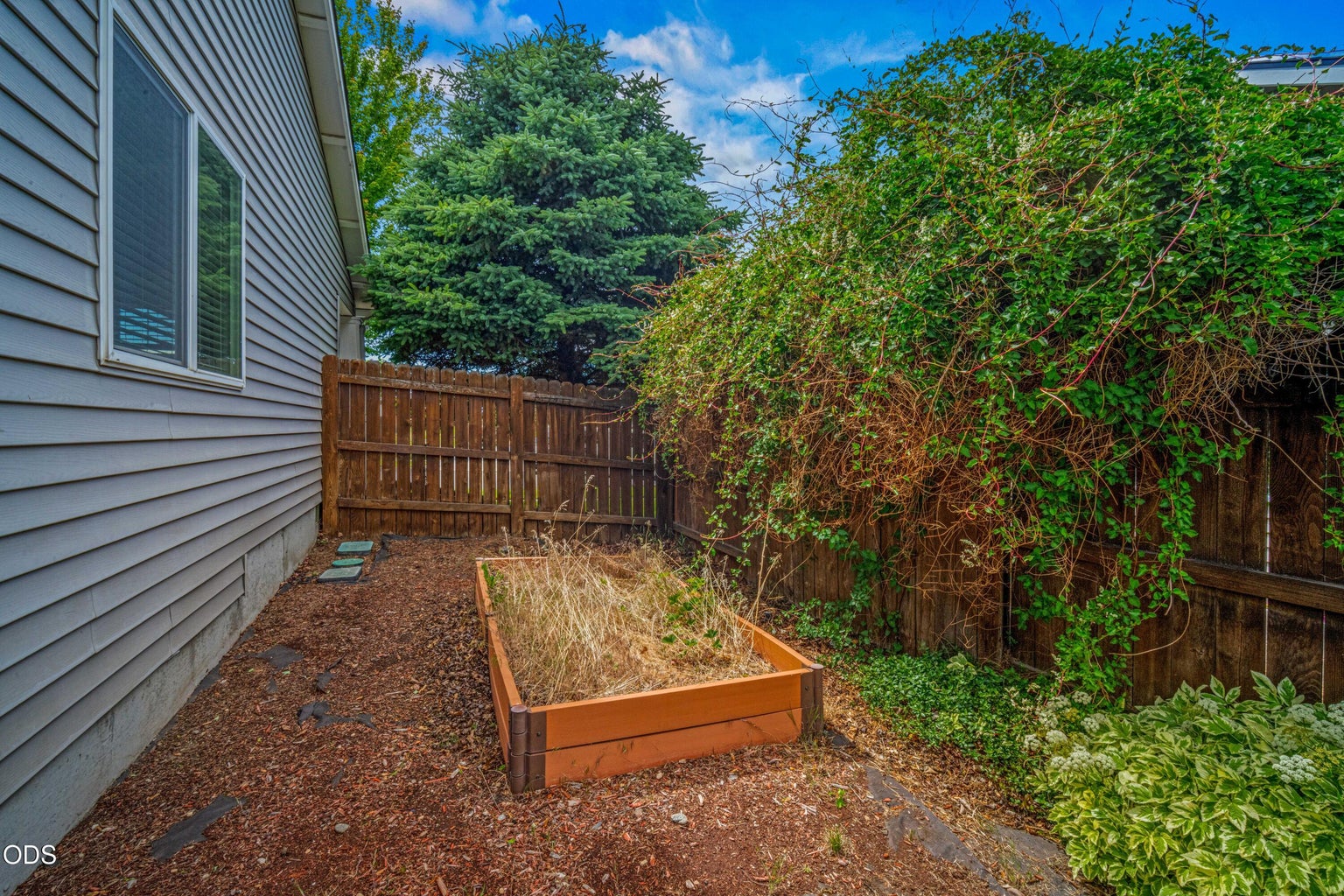 A raised garden bed and side yard area offer space for seasonal planting, herbs, vegetables, or low-maintenance landscaping.