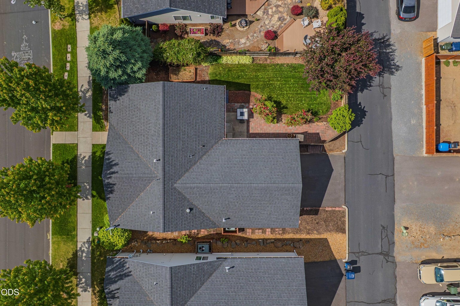 A top-down aerial view shows the home’s footprint, fenced yard, paver patio, rear garage access, and efficient lot layout.