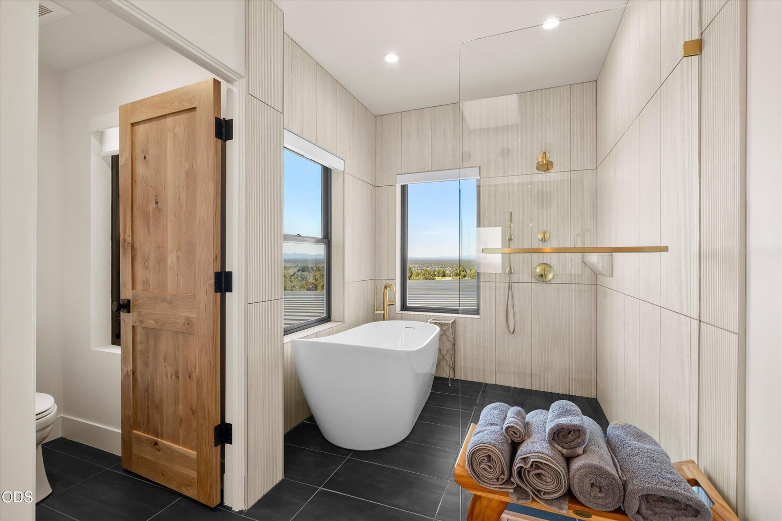 The shower is wet room style next to a freestanding soaking tub, and there is a separate water closet