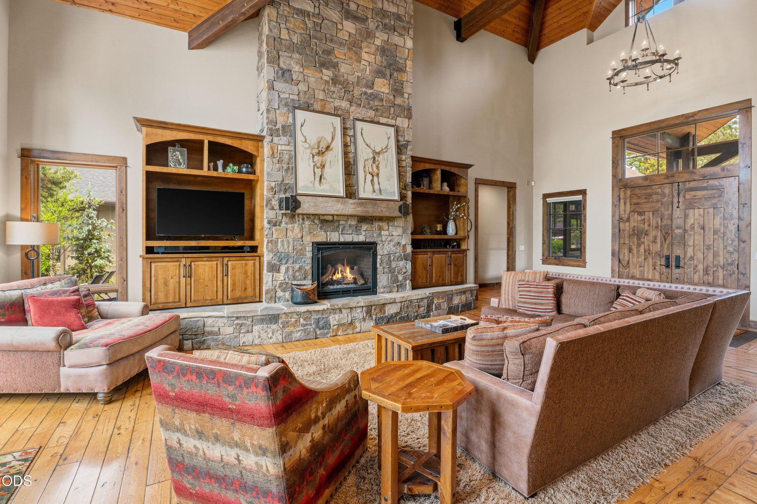 Warm wood finishes, custom built-ins, and a stunning stone fireplace create an inviting gathering space filled with natural light.
