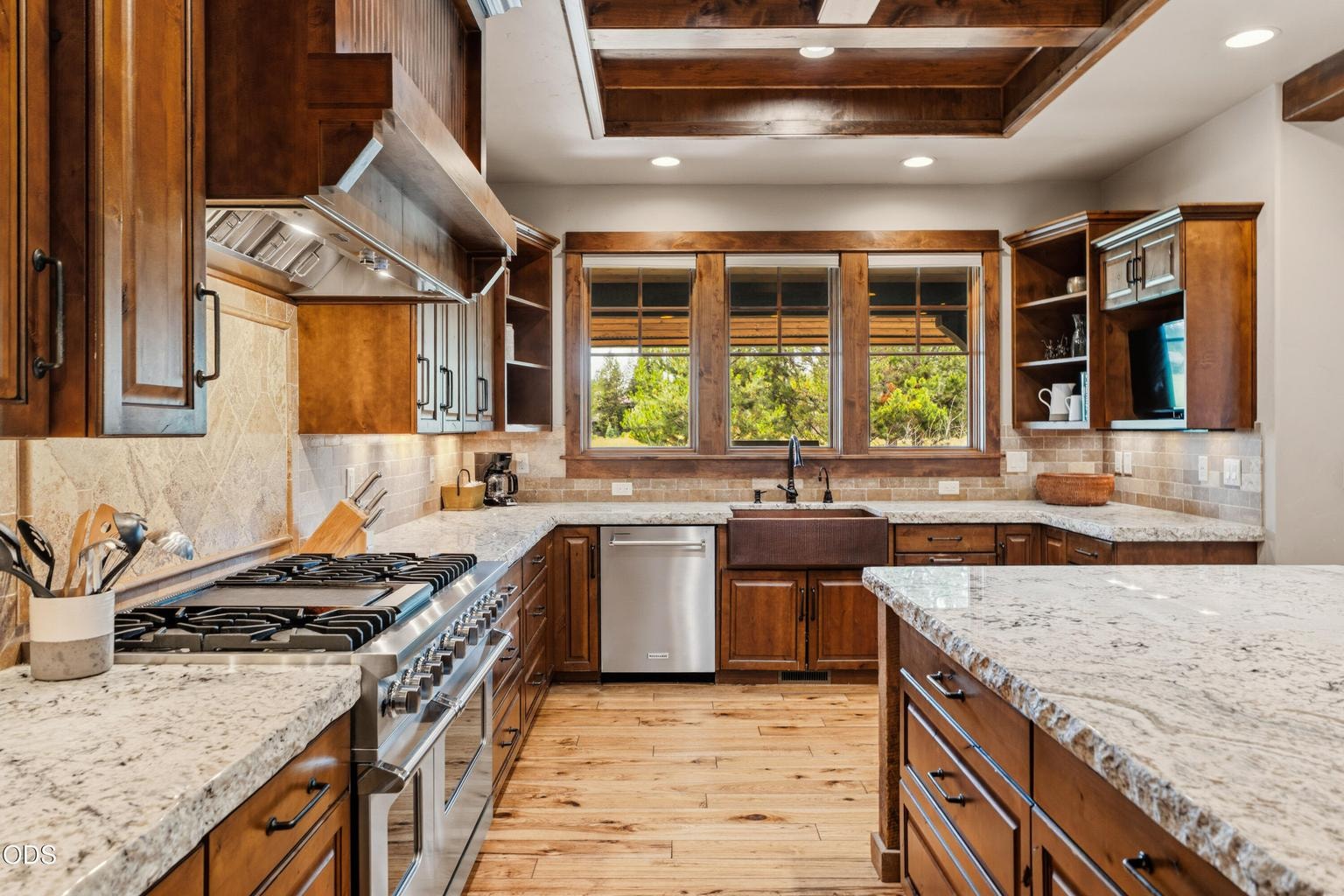 The gourmet kitchen is thoughtfully designed with premium stainless steel appliances, a professional gas range, custom cabinetry, and a copper farmhouse sink.