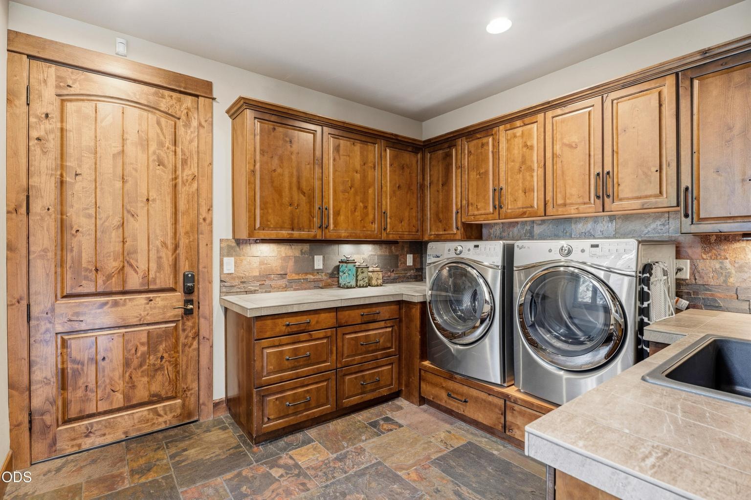 The spacious mudroom and laundry room offers abundant custom cabinetry, generous workspace, a utility sink, and direct access to the oversized three-car garage.
