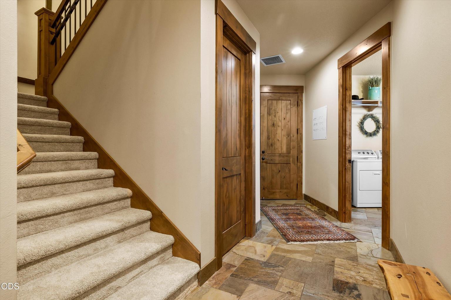 Hallway off foyer leads to laundry room, garage, and stairs with ample under-stair storage